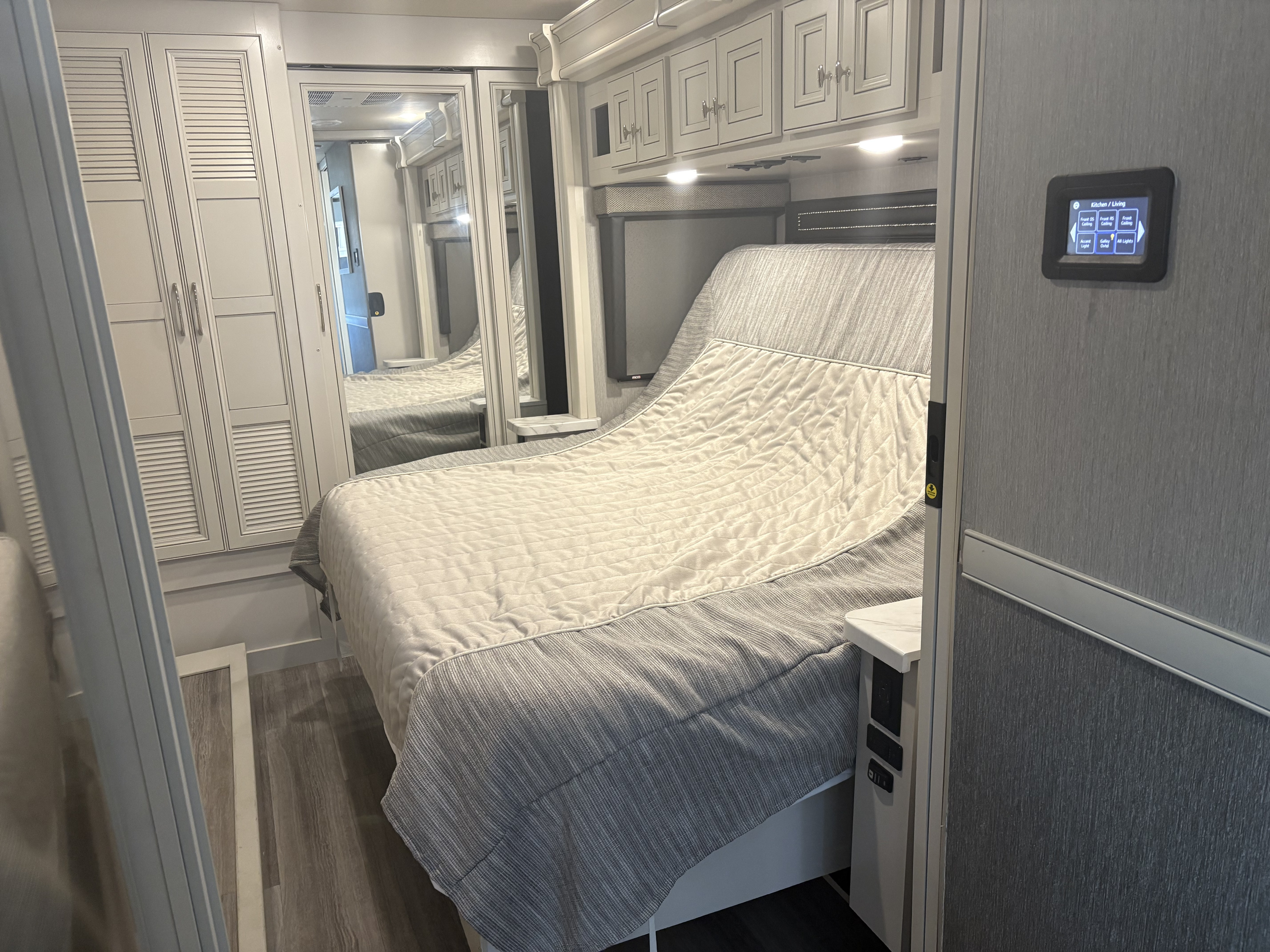 This RV rental bedroom features a comfy bed, mirrored closets, overhead cabinets, and a digital lighting control panel.. Fleetwood Frontier 2022