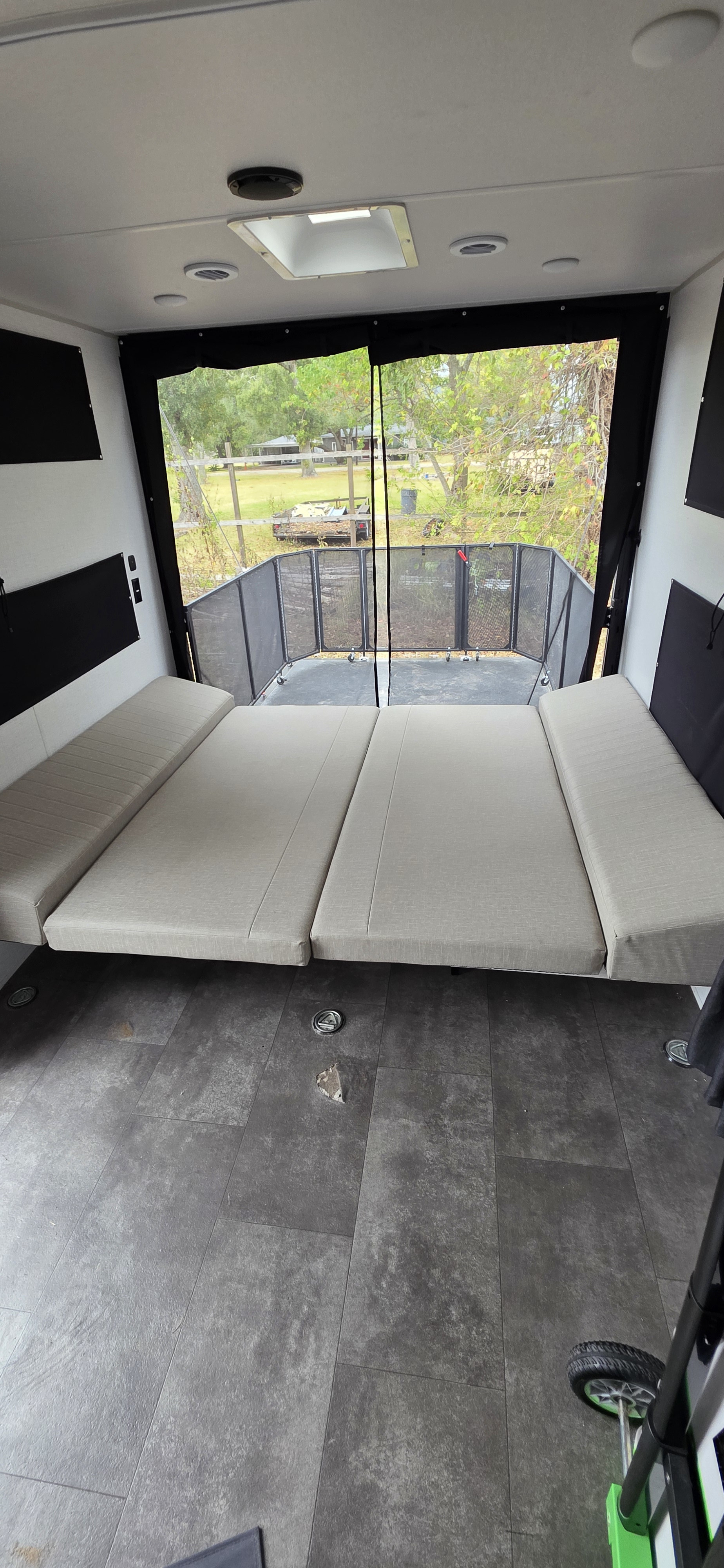 RV rental interior with convertible seating/beds, an open back patio with screen, and a dark tiled floor.. Forest River Wildwood FSX Platinum 2024