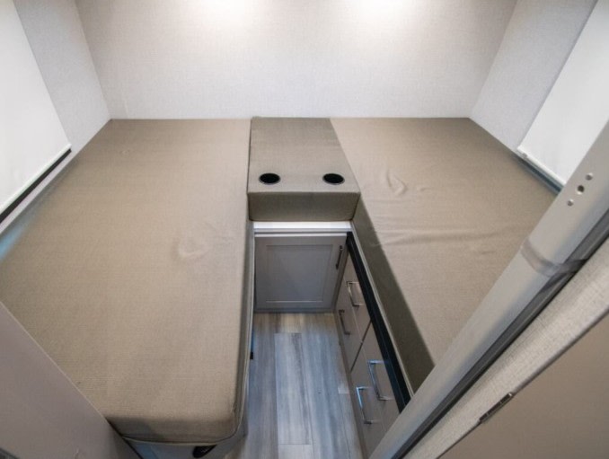 RV rental interior featuring two comfortable bunk beds, a central console with cup holders, and storage drawers below.. Thor Motor Coach Four Winds 2026
