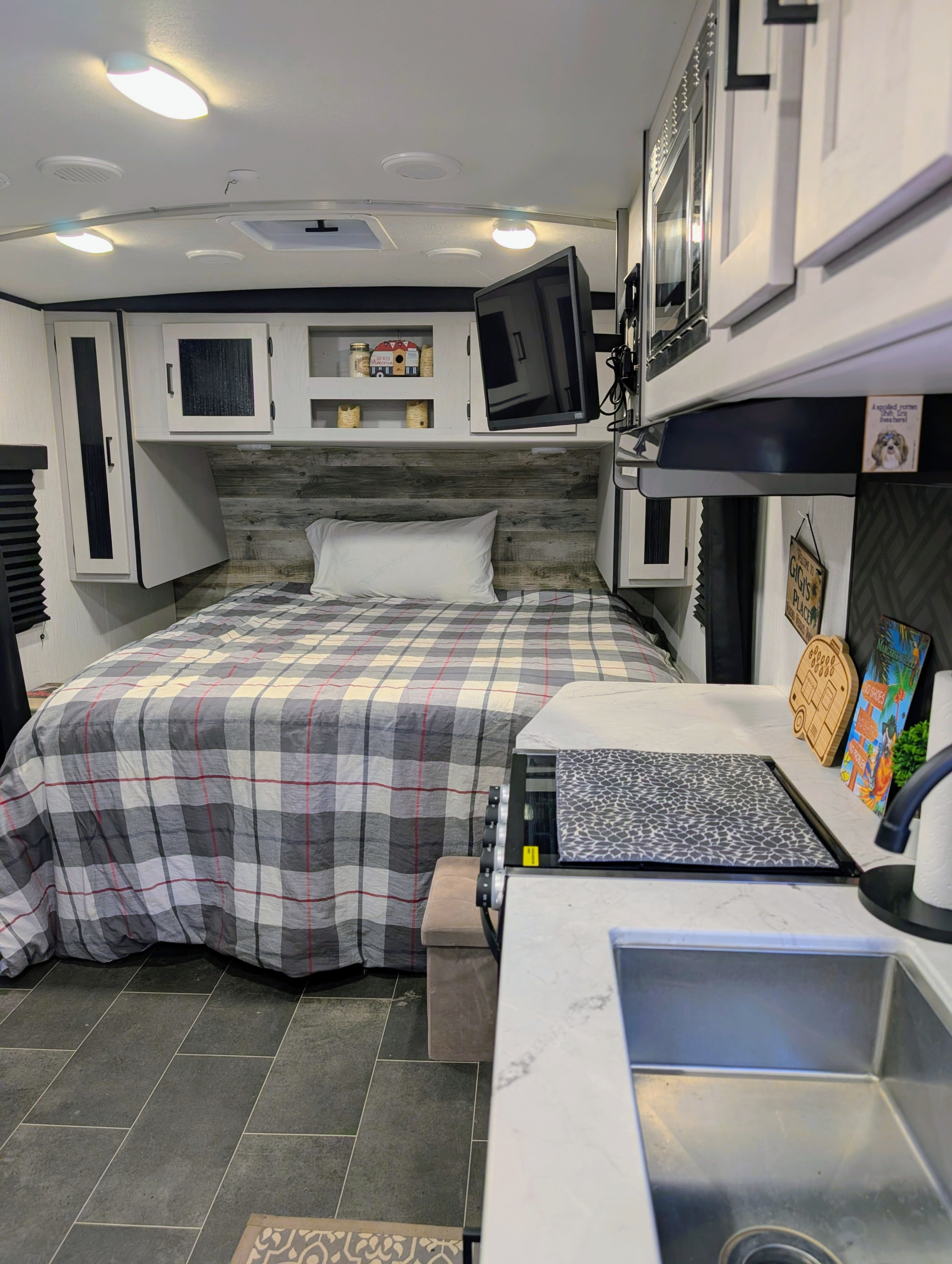Spacious RV rental featuring a comfortable bed with plaid bedding, kitchen counter/sink, and entertainment for road trip adventures.. Heartland RVs Mallard 2022