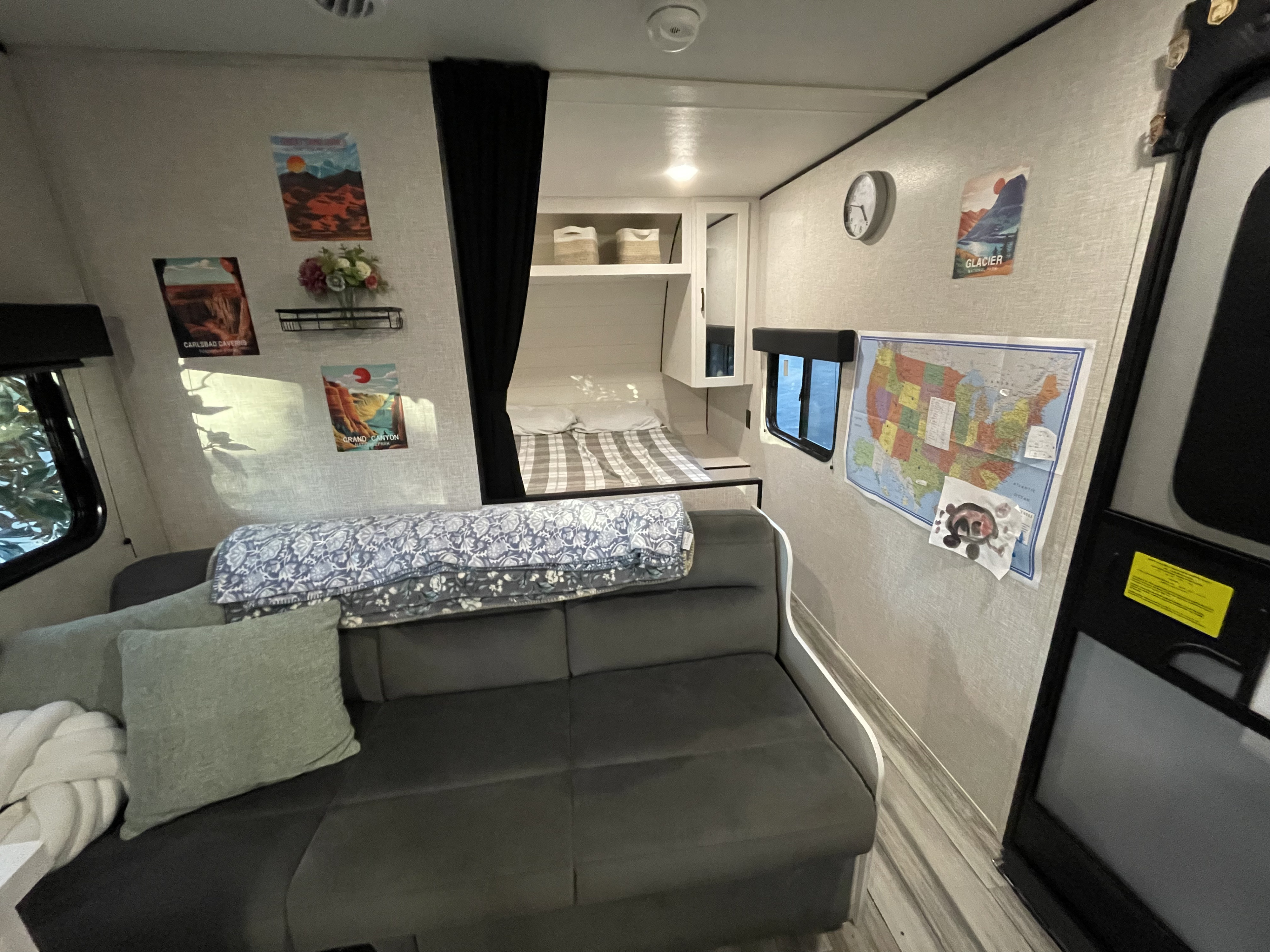 Cozy RV rental interior showing a sofa, bunk bed, US map, and national park posters on the wall.. Jayco Jay Flight SLX 2025