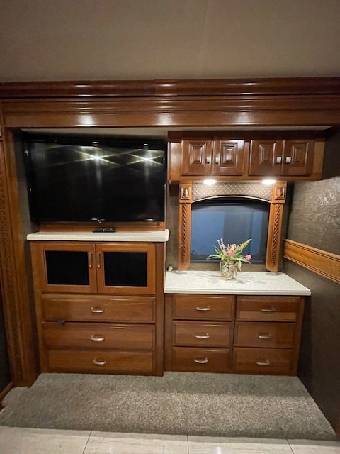RV rental: Bedroom features built-in rich wood entertainment center with TV, storage drawers, cabinets, and window.. Holiday Rambler Endeavor 2018