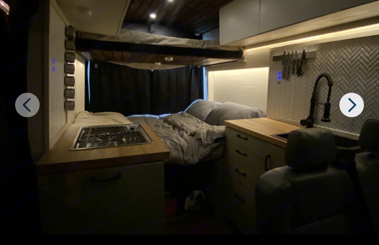Cozy RV rental interior featuring a bunk bed, full kitchen with stove and sink, plus a stylish compact living space.. Ford Transit 2015