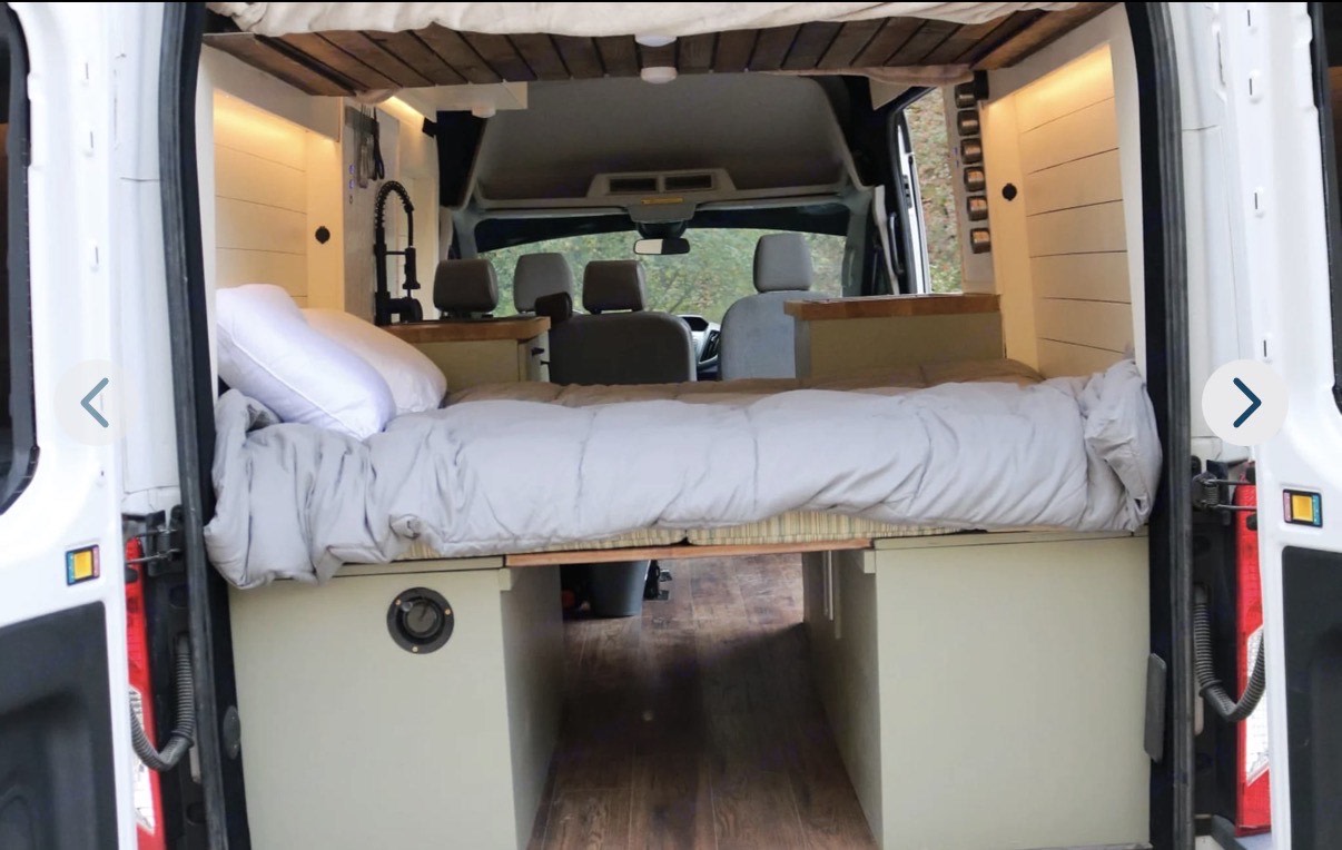 Cozy RV rental camper van interior with bed, under-bed storage, sink, and front cabin view. Ideal for your next adventure.. Ford Transit 2015