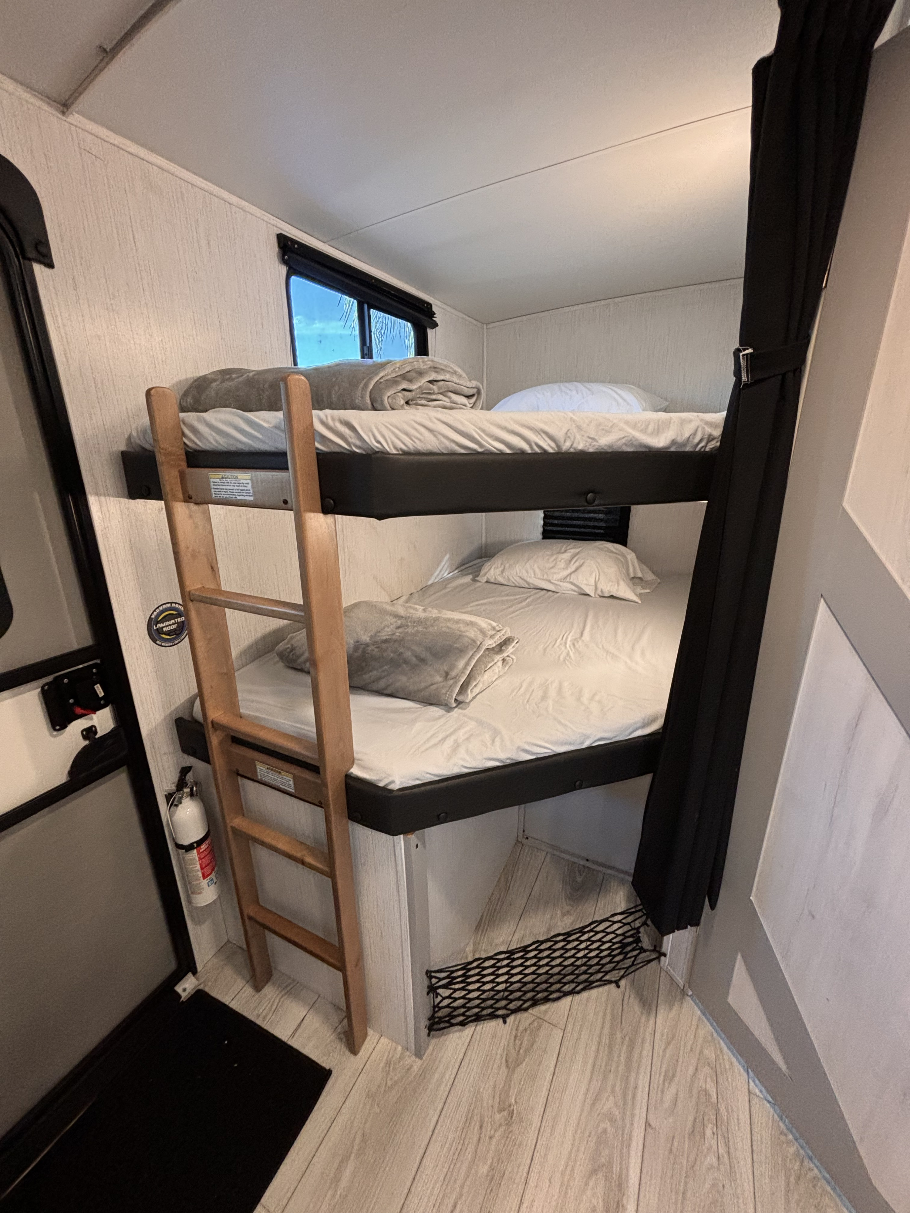 Cozy RV rental bunk beds with a ladder, window, and fire extinguisher for safe travel and sleeping in your camper.. Heartland RVs North Trail 2022
