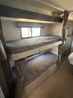 RV rental bunk beds: two cozy sleeping bunks with dark bedding, privacy curtains, and a window. Ideal for camper adventures.. Gulf Stream Conquest 2022