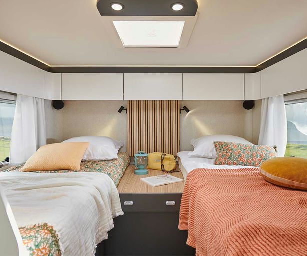 Cozy RV rental bedroom featuring two single beds, warm lighting, and scenic window views for comfortable travel.. Pilote P726FGJ 2026