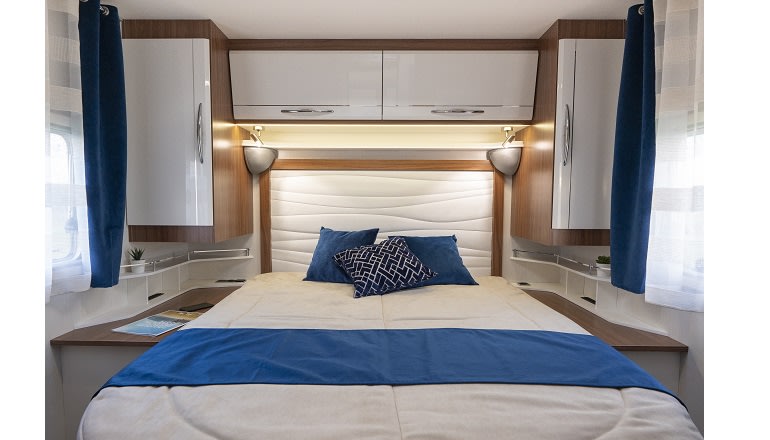 Spacious and cozy RV rental bedroom with a large bed, blue accents, reading lights, and convenient storage.. PILOTE P726 C 2026