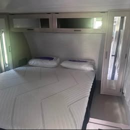 Enjoy comfortable travel in this RV rental's bedroom, featuring a white mattress, pillows, and overhead storage cabinets.. Forest River Salem FSX 2024