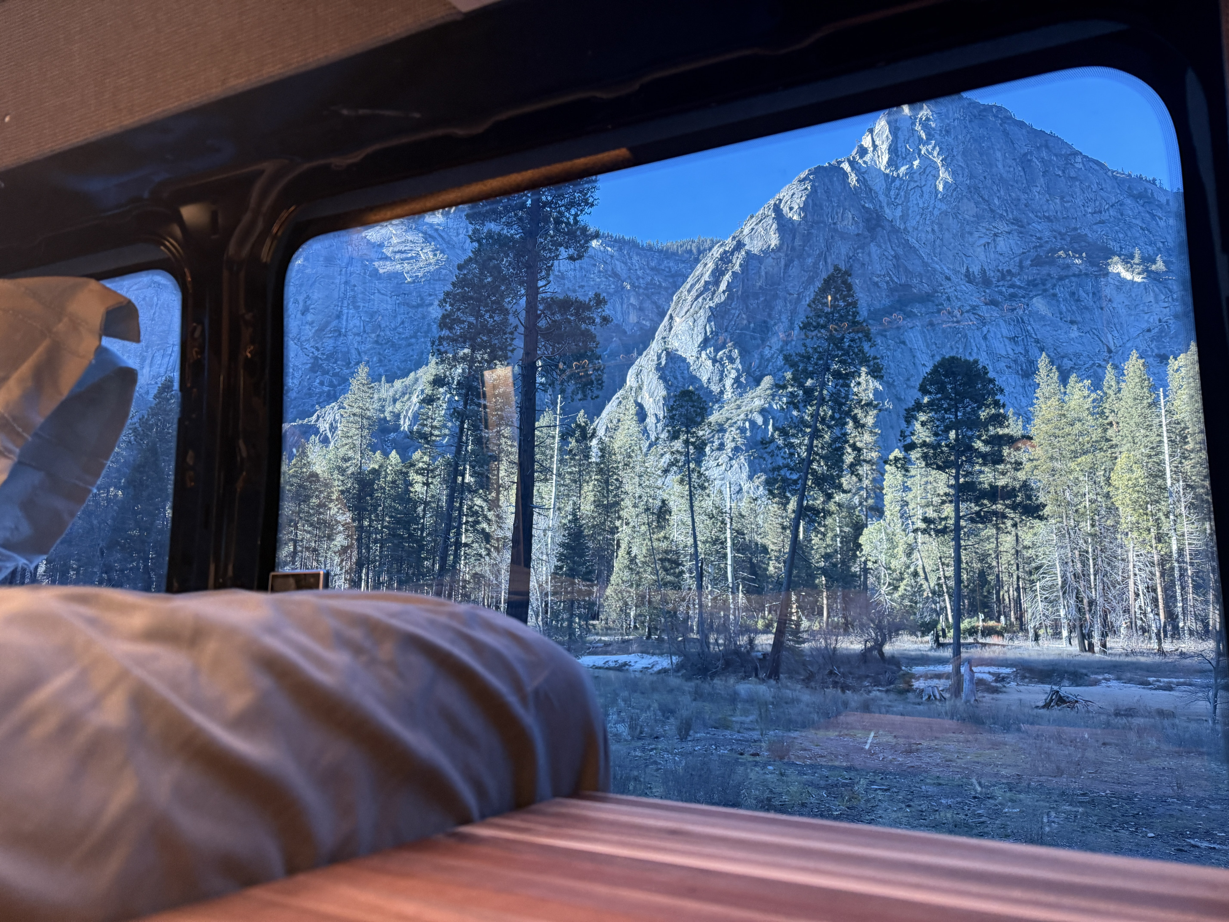 Gaze at majestic mountains and a serene forest from the window of your comfortable *rv rental*, offering a cozy nature escape.. Ford Transit 2023