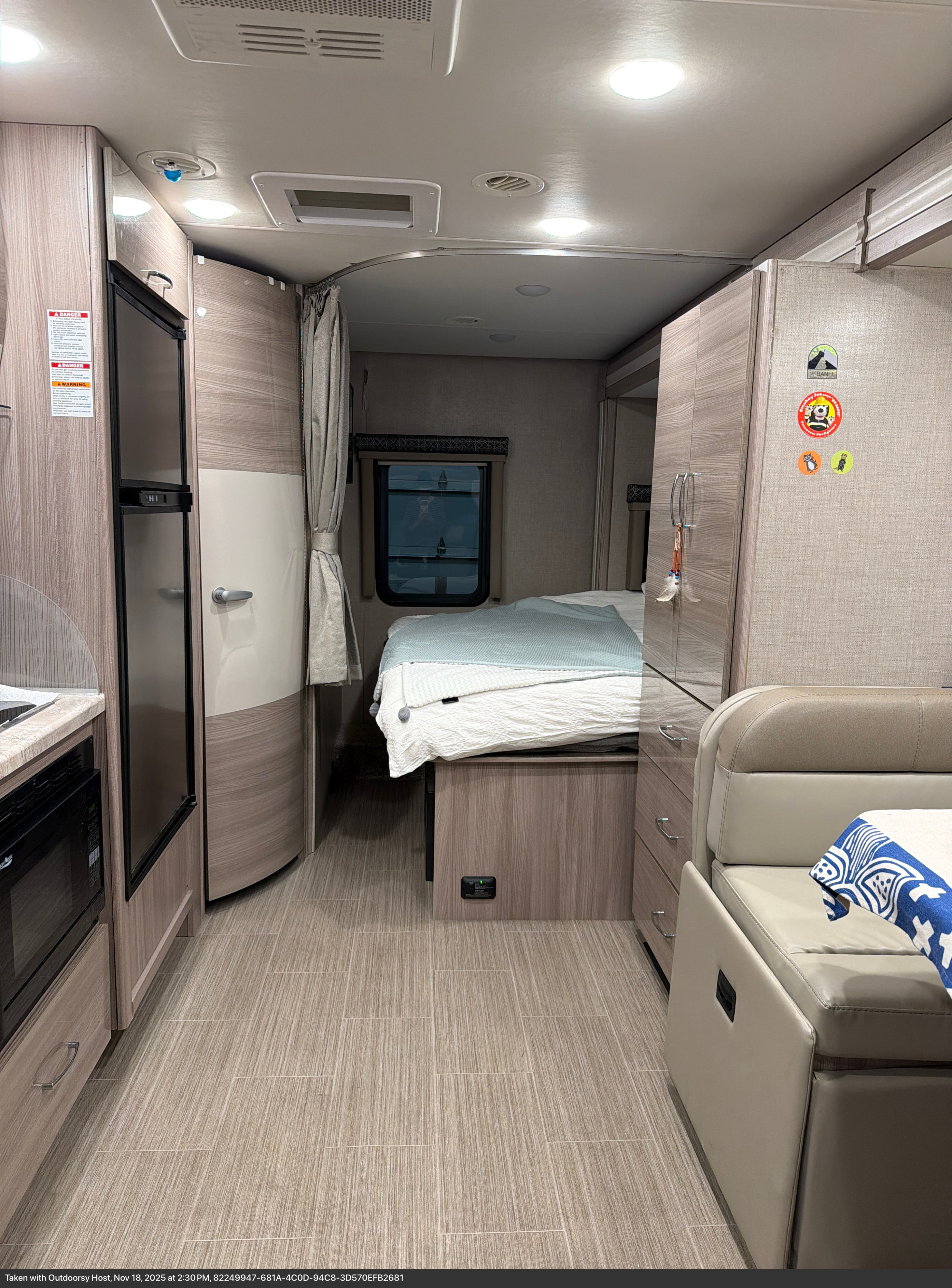 Cozy RV rental interior featuring a comfortable bed, compact kitchen, and dinette seating. Ready for adventure!. Thor Tiburon SV 2023