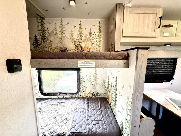 Cozy, family-friendly RV rental interior featuring themed bunk beds with a forest animal wallpaper, perfect for adventure.. Heartland RVs Mallard 2025
