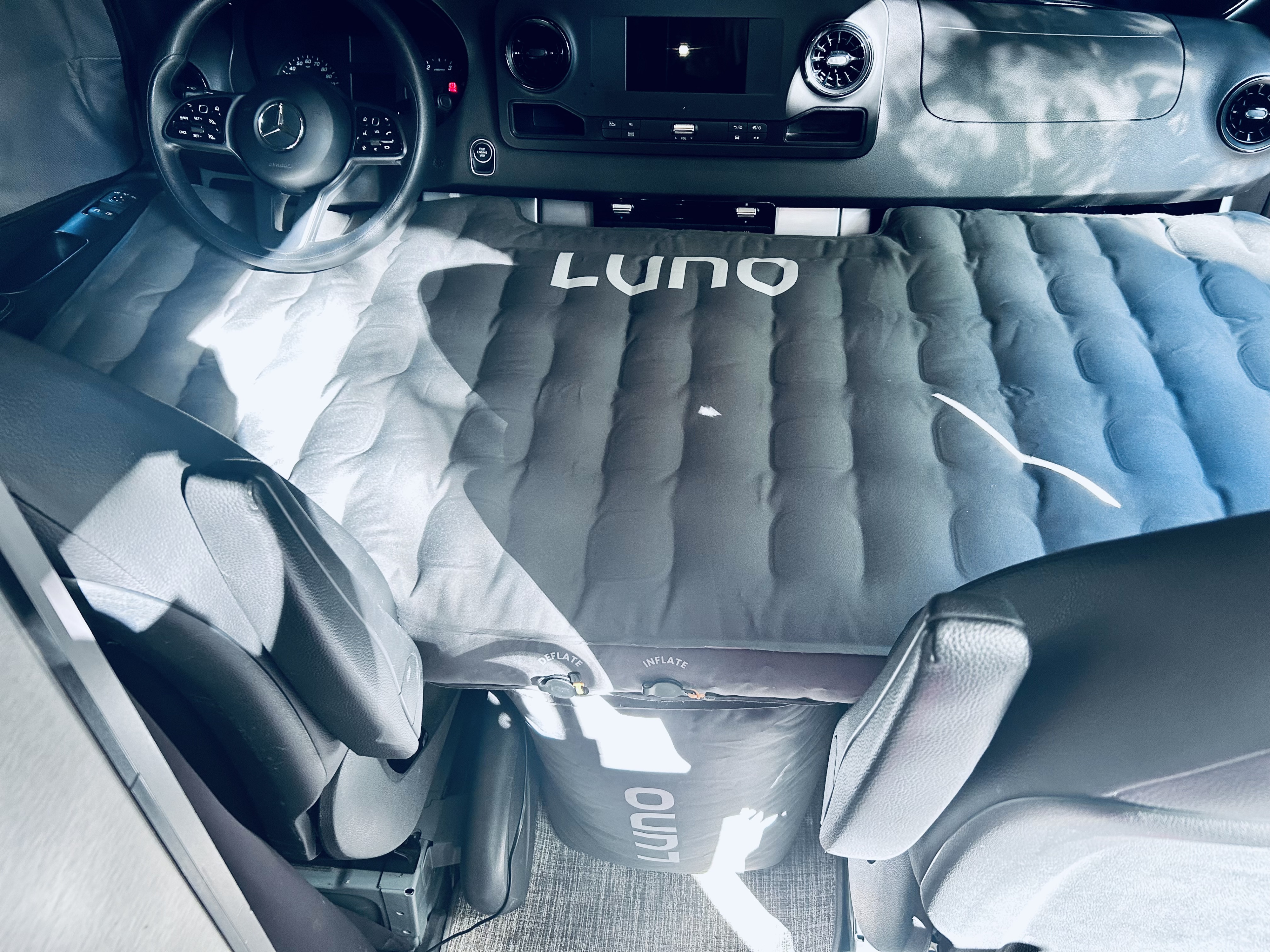 Interior of an RV rental van with a LUNO air mattress converting front seats into a bed. Ideal for comfortable van camping.. Thor Synergy 2022