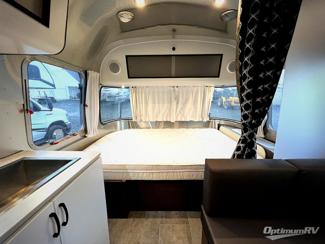 Interior of a modern rv rental: bed, sink, and sofa in a clean, metallic space. Ready for your journey.. Airstream Caravel 2022