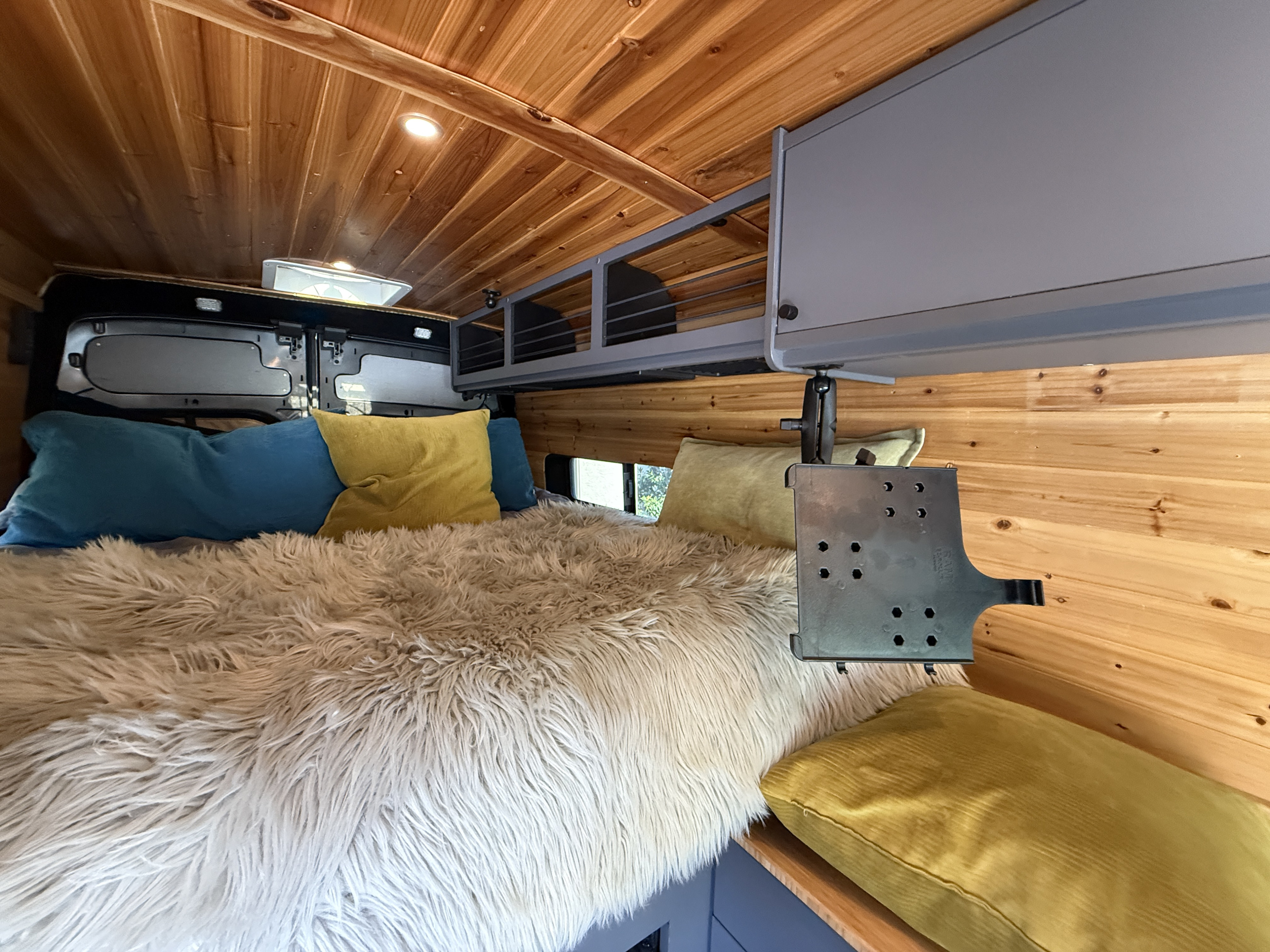 Cozy RV rental interior with wooden walls, a plush bed, and overhead storage. Features a screen mount for entertainment.. Ford Transit Extended High-Roof 2018