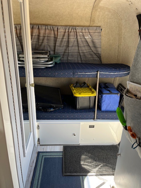 Interior of an RV rental: features a bunk bed, organized storage for gear, floor mats, and a hanging organizer.. Scamp 16' 2001
