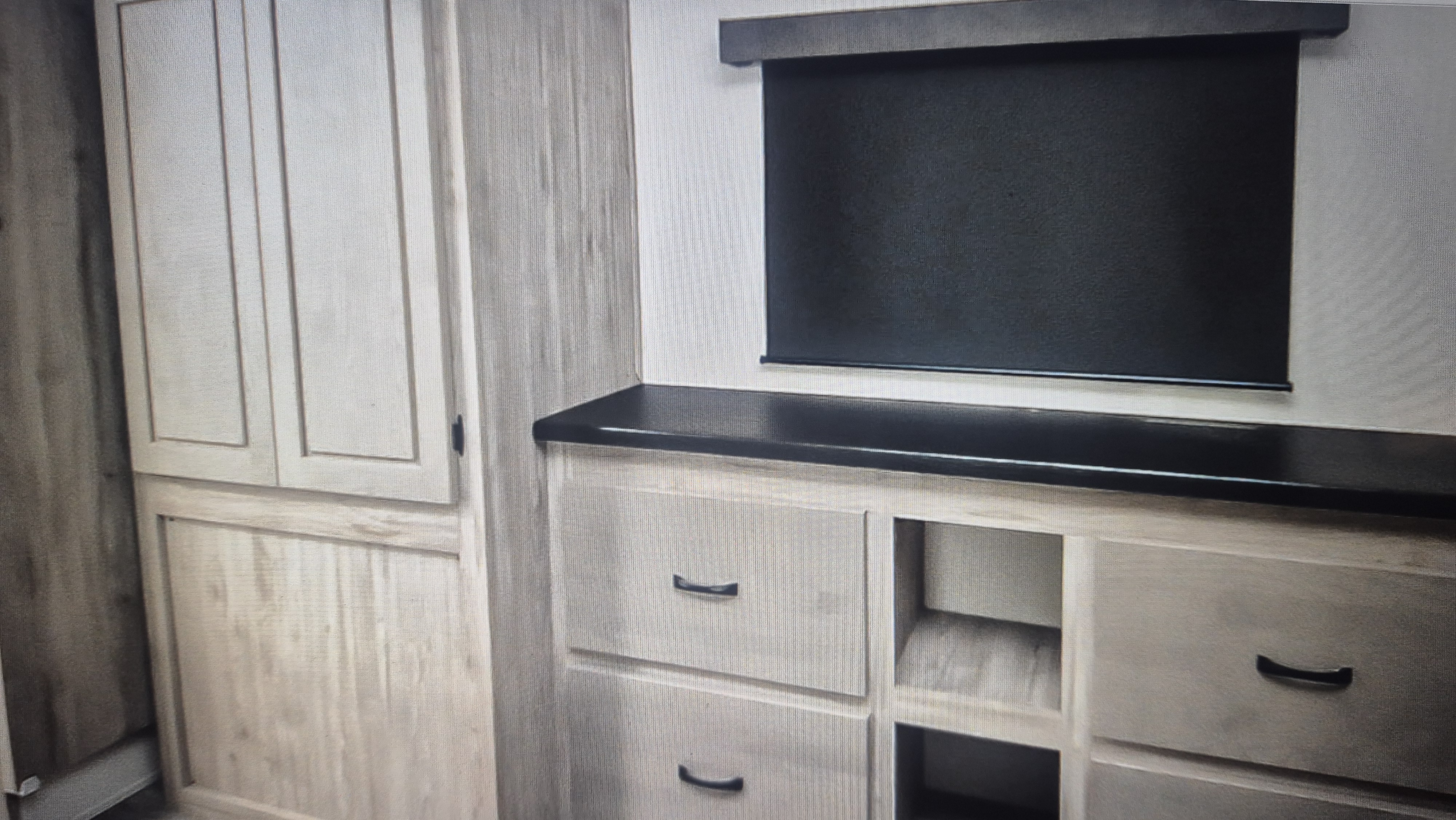 RV rental interior showing light wood cabinetry, a black countertop, and a pull-down privacy blind for comfort.. Coachman Chaparral 375BAF 5 slide out Coachmen Chaparral 5 slideout 2025