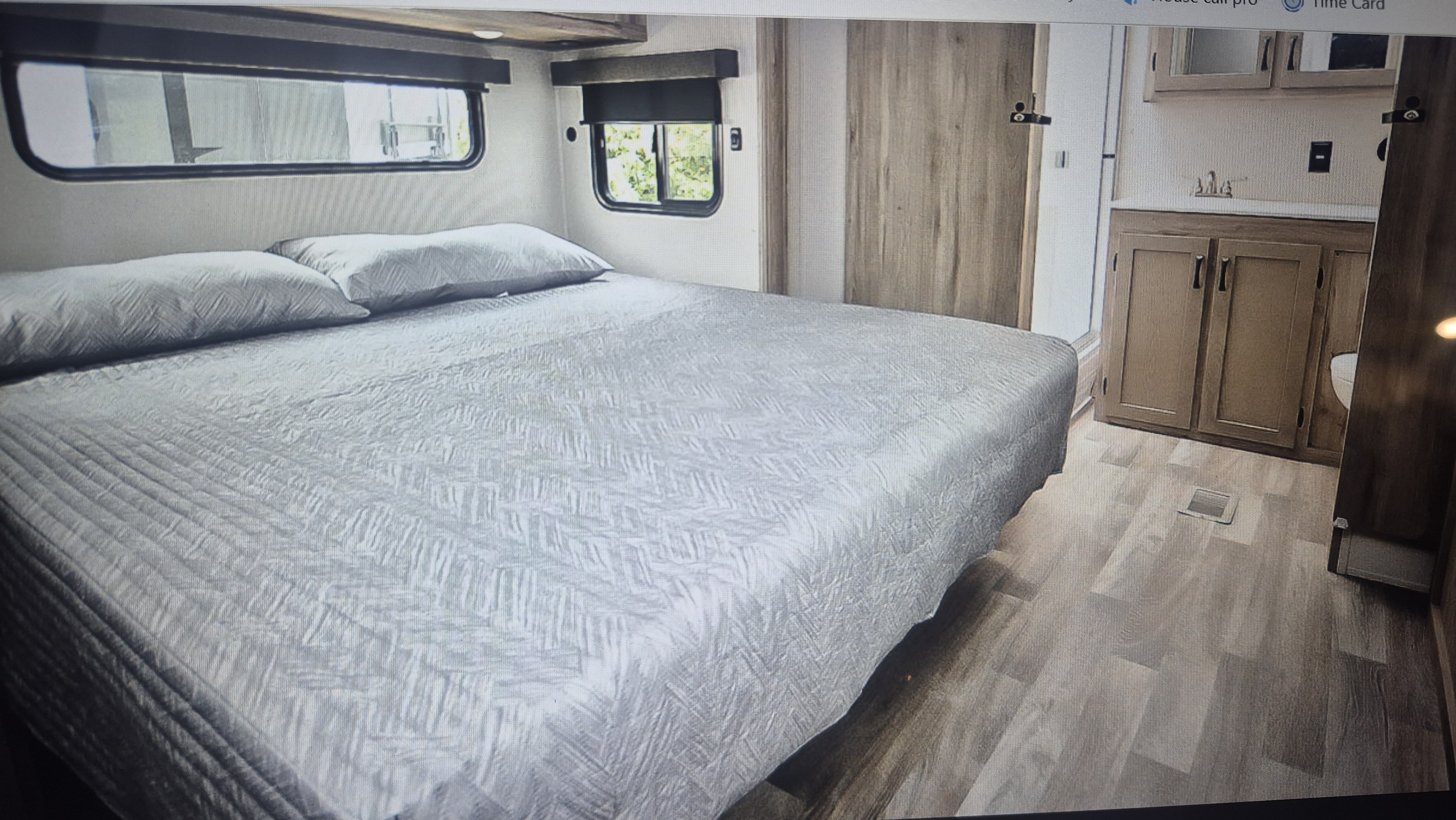 Spacious RV rental bedroom with queen bed, windows, and an adjacent bathroom vanity, perfect for comfortable travel.. Coachman Chaparral 375BAF 5 slide out Coachmen Chaparral 5 slideout 2025