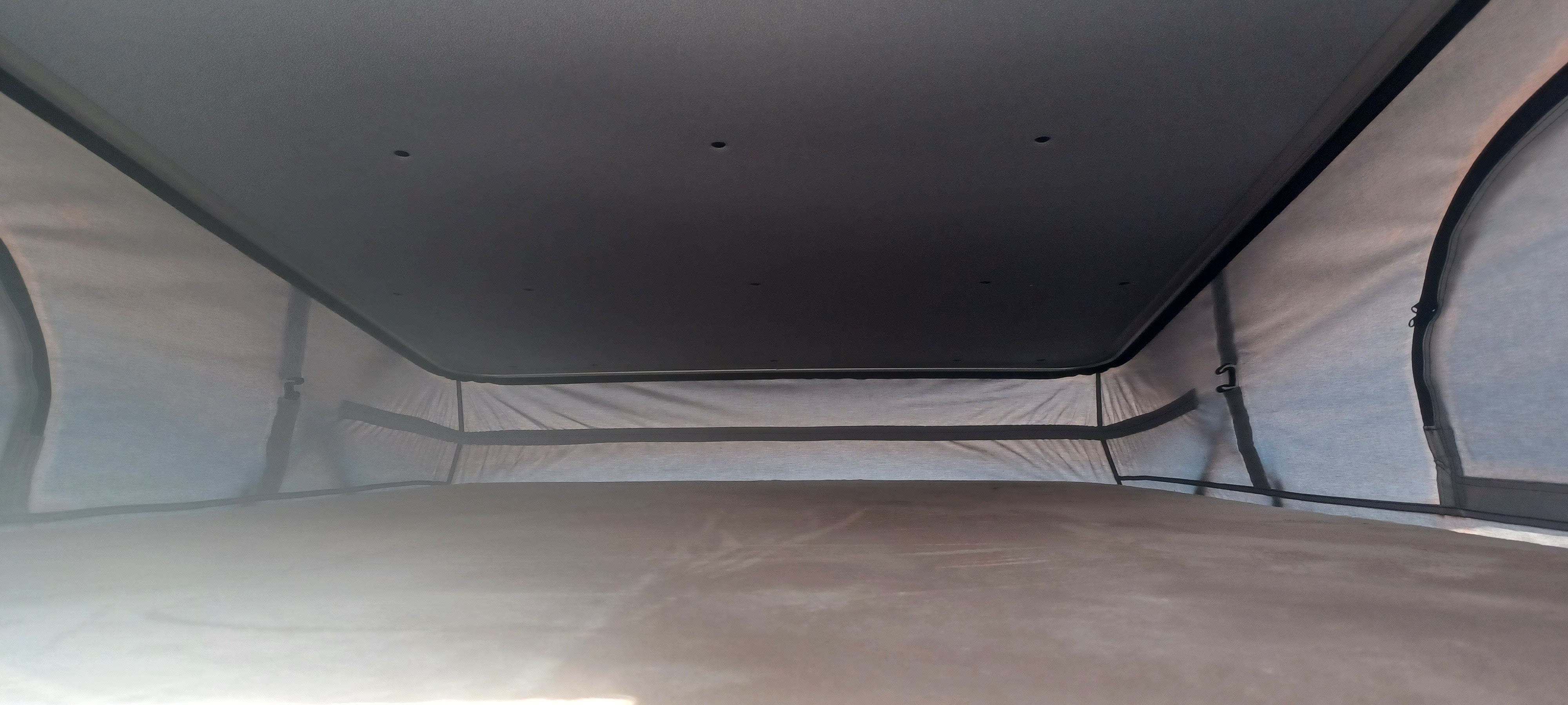 Interior of an RV rental pop-top camper: a cozy sleeping area with fabric walls and ceiling lights, ready for travel.. Thor Scope 2023