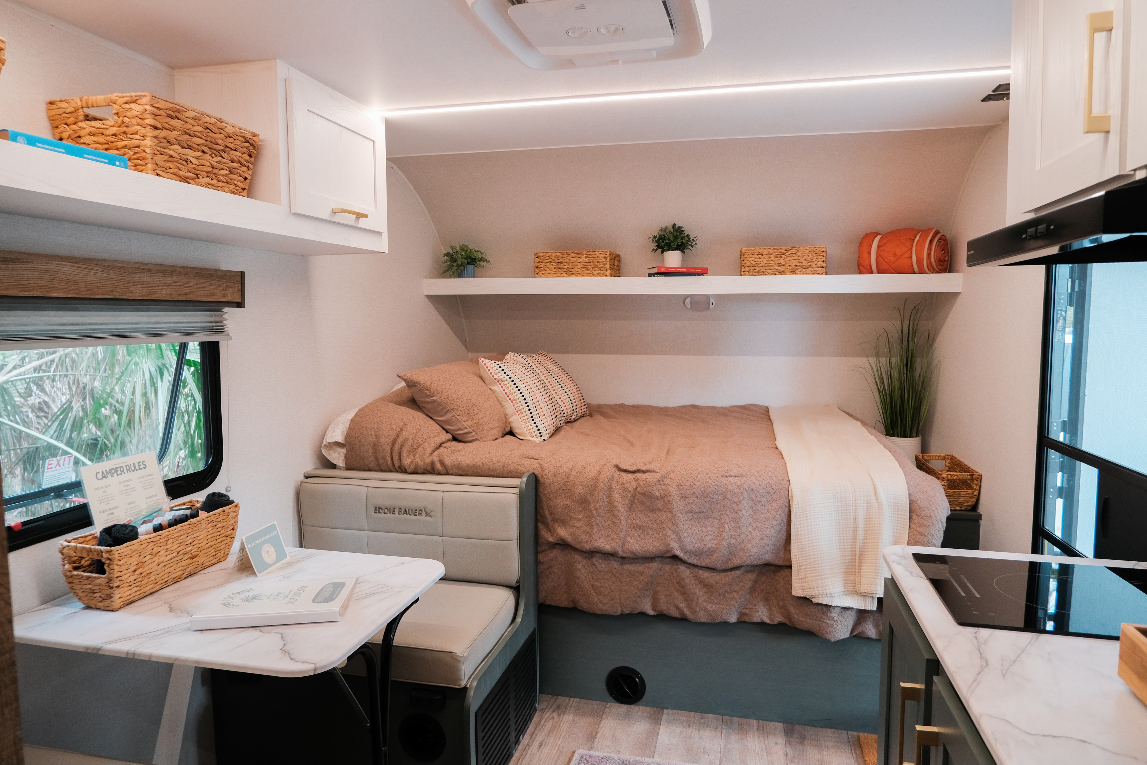 Cozy and functional RV rental interior featuring a comfortable bed, compact kitchen, and a small dinette area.. Heartland RVs Eddie Bauer 2025