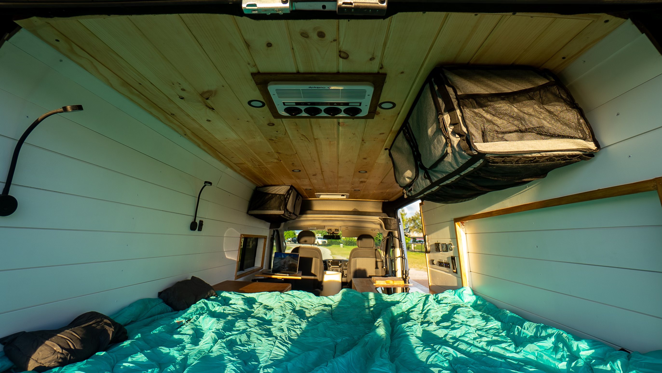Cozy rv rental camper van interior with a teal bed, wooden ceiling, and front cabin view, perfect for road trips.. Ram Promaster 2500 2021