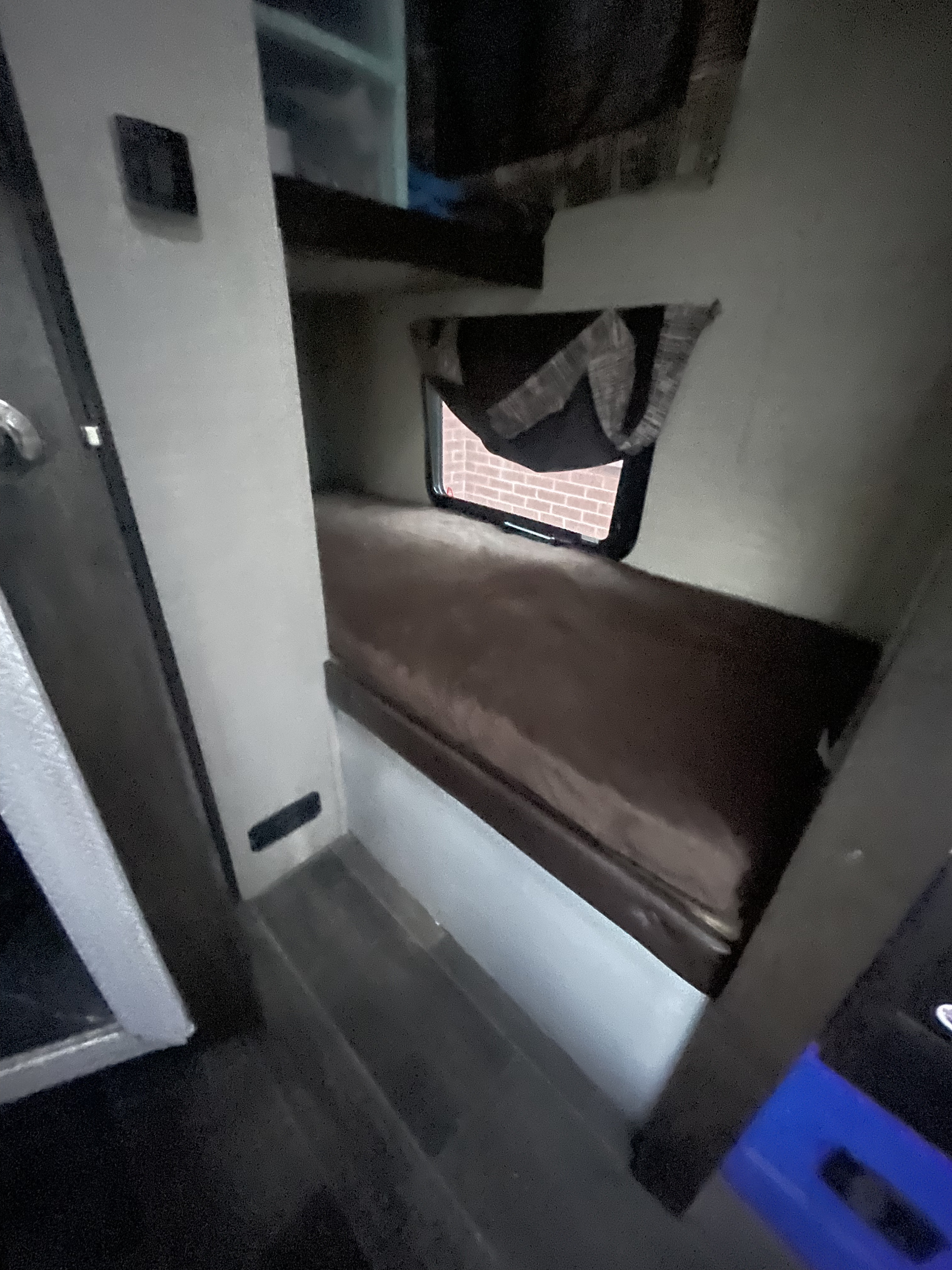 RV rental bunk bed. Lower bed with brown mattress, window with brick wall view, & wall vent. Functional space.. Keystone RV Bullet Ultra Lite 2018