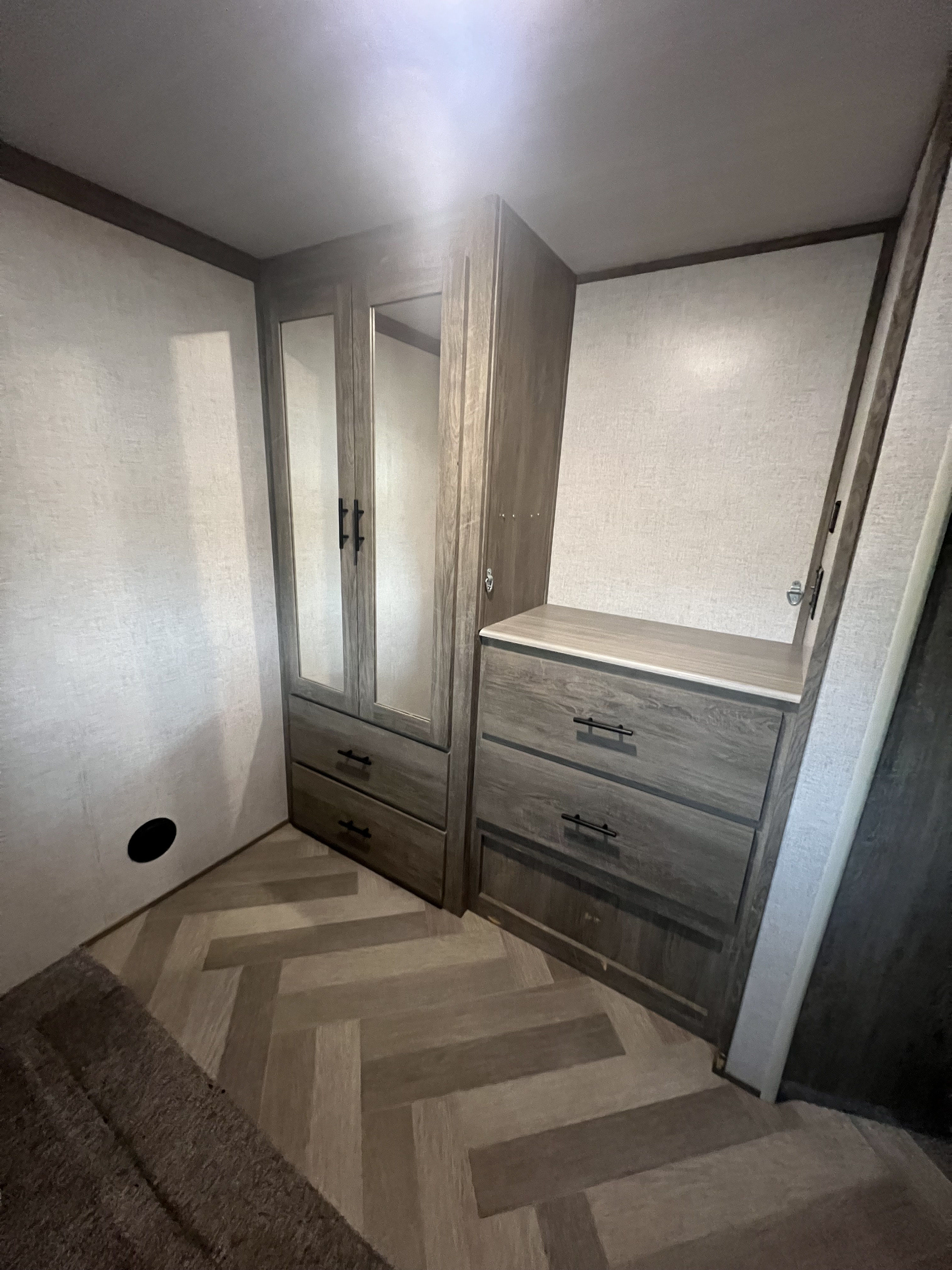 RV rental interior featuring a mirrored wardrobe with drawers, a dresser, and stylish herringbone flooring, offering ample storage.. Forest River Salem Hemisphere 2020