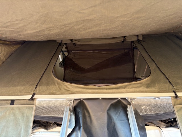 Explore the cozy interior of this rv rental rooftop tent, featuring a mesh window for ventilation. Perfect for camping!. Runaway Trailers The Range Runner 2024