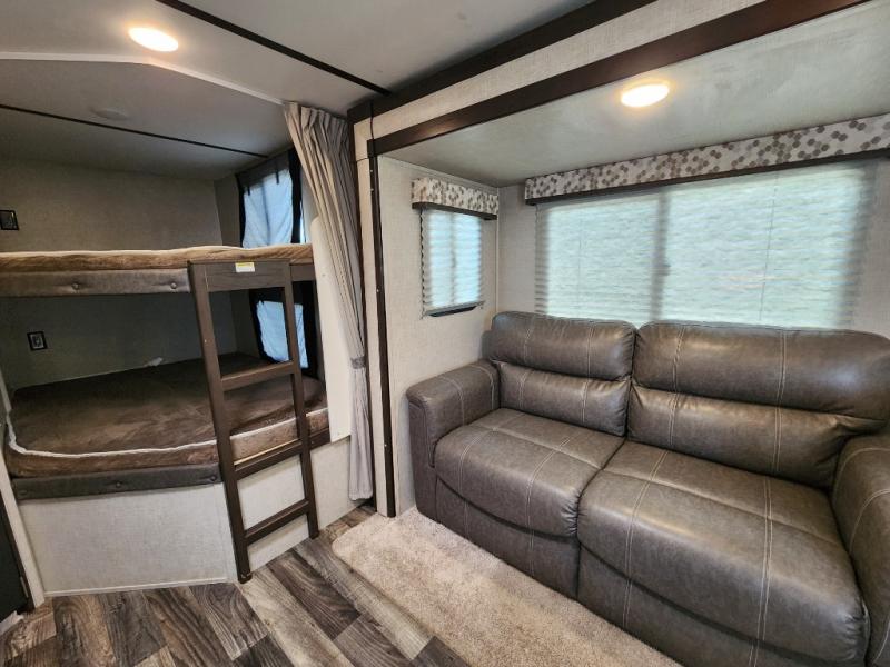 Comfortable RV rental interior with bunk beds and a two-seater sofa, offering a cozy living space.. Keystone RV Bullet Ultra Lite 2019