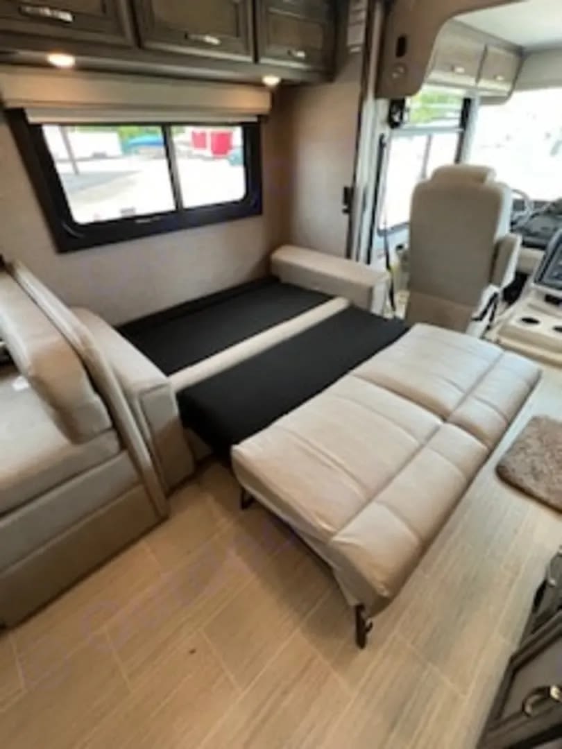 This rv rental features a versatile sofa-bed, a large window, overhead storage, and a glimpse of the driver's cockpit.. Entegra Coach Vision XL 2023