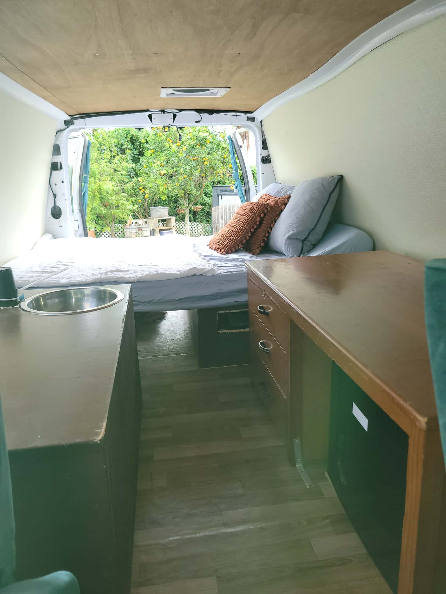 Cozy RV rental interior with bed, sink, desk, and outdoor view. Perfect for mobile living in this camper van.. Ford Econoline 2007