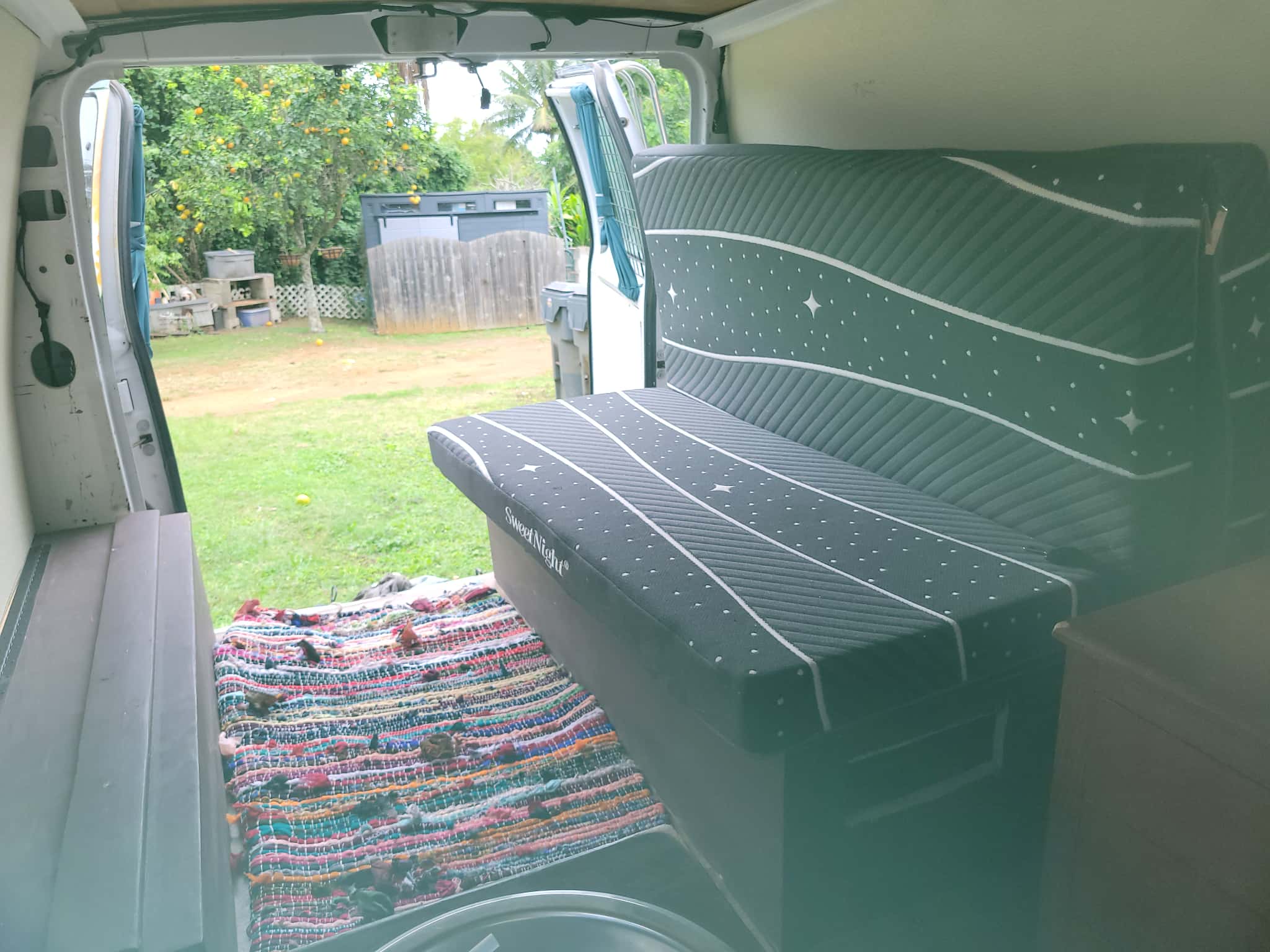 Cozy van interior with starry bench, colorful rug, and a scenic outdoor view, perfect for your next rv rental adventure.. Ford Econoline 2007