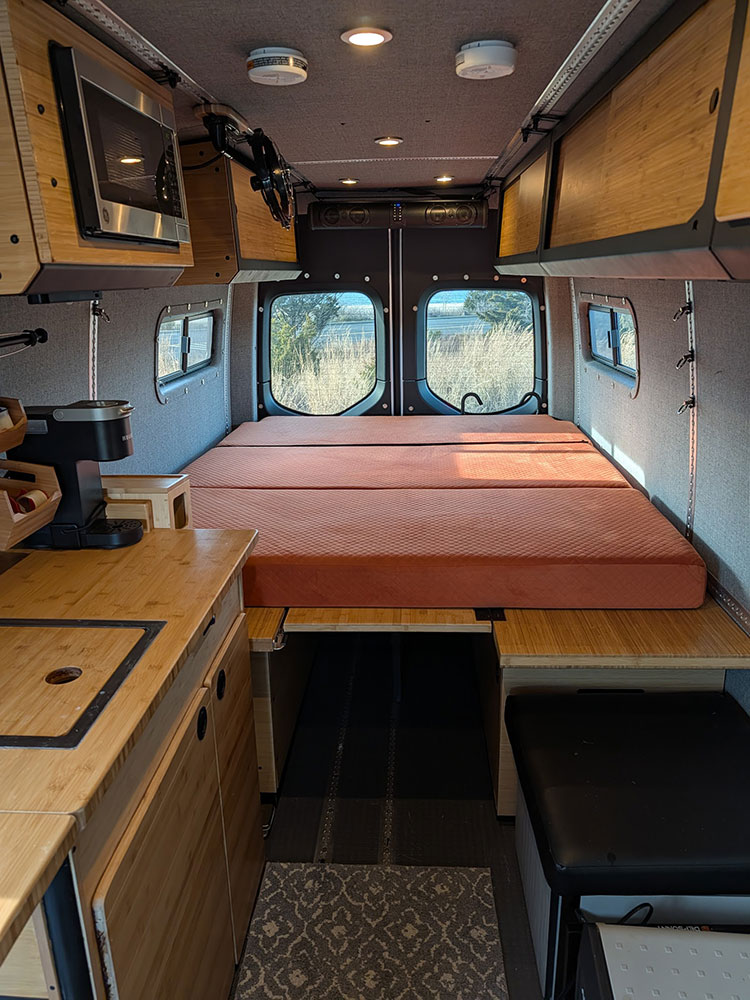 Cozy van life rv rental: a well-equipped interior with bed, kitchenette, and storage for comfortable travel adventures.. Winnebago Adventure Wagon 2023