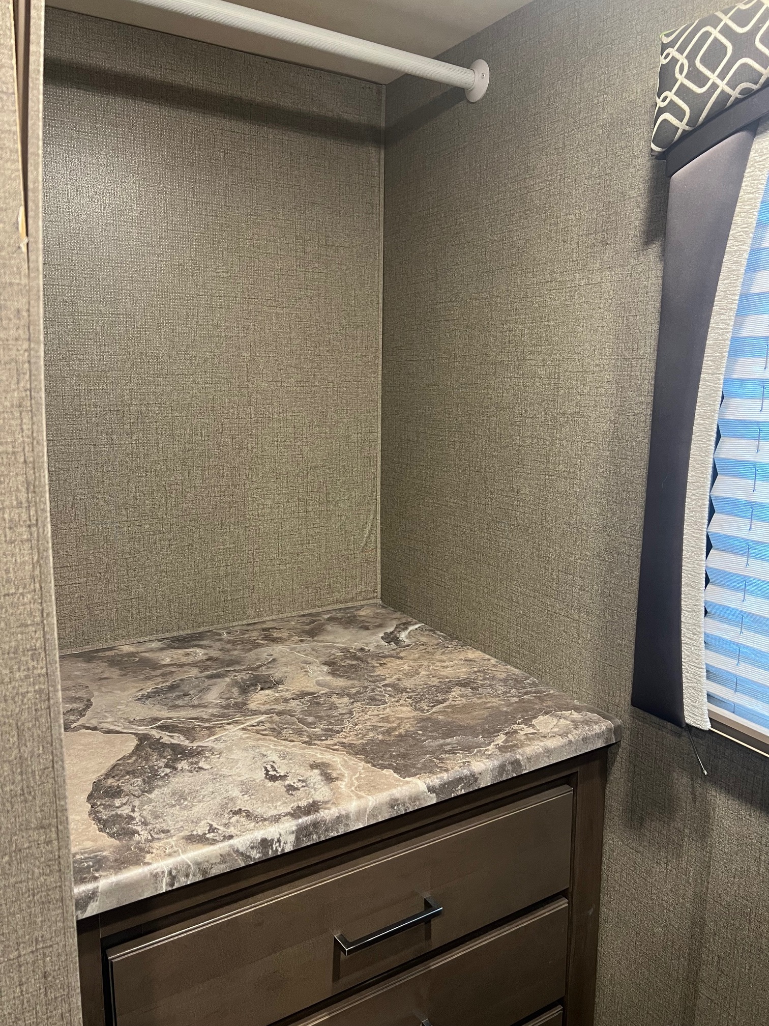 RV rental closet with a hanging rod, marbled countertop, drawers, and window blinds. Compact storage for travel.. Thor Chateau 2021