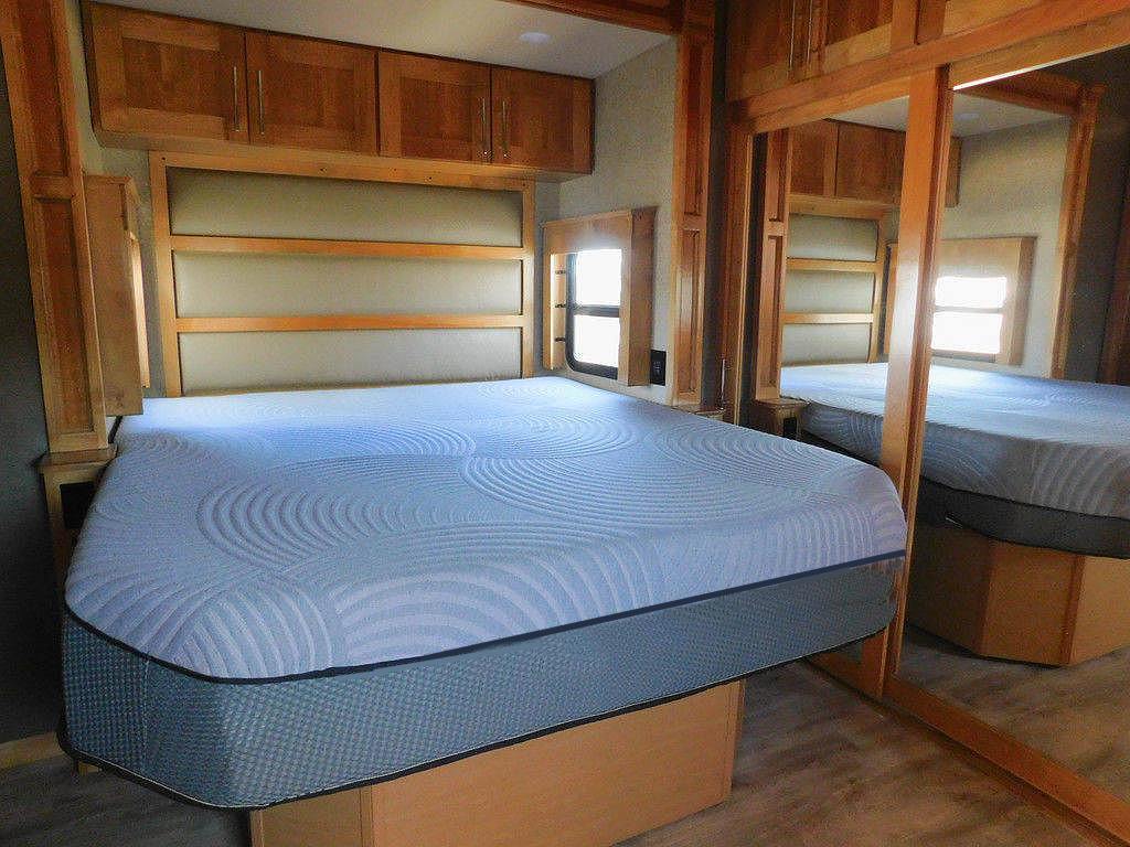 RV rental bedroom featuring a comfortable mattress, overhead storage, and mirrored closet. Ideal for a cozy travel stay.. Vanleigh RV Vilano 2018