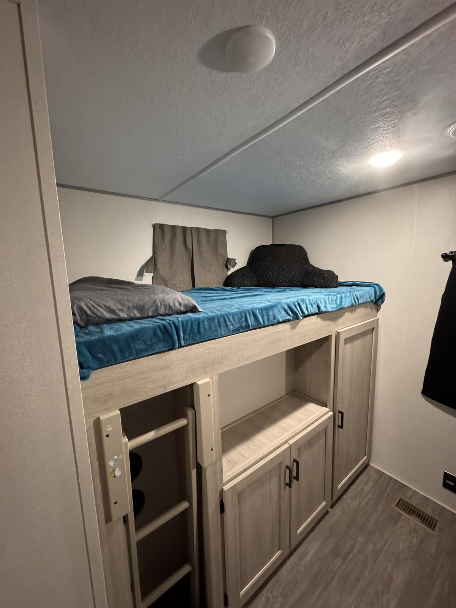 RV rental: A cozy bunk bed sleeping area with a blue blanket, gray pillow, and ample storage cabinets below. Ladder access.. Forest River Aurora Aurora 2024