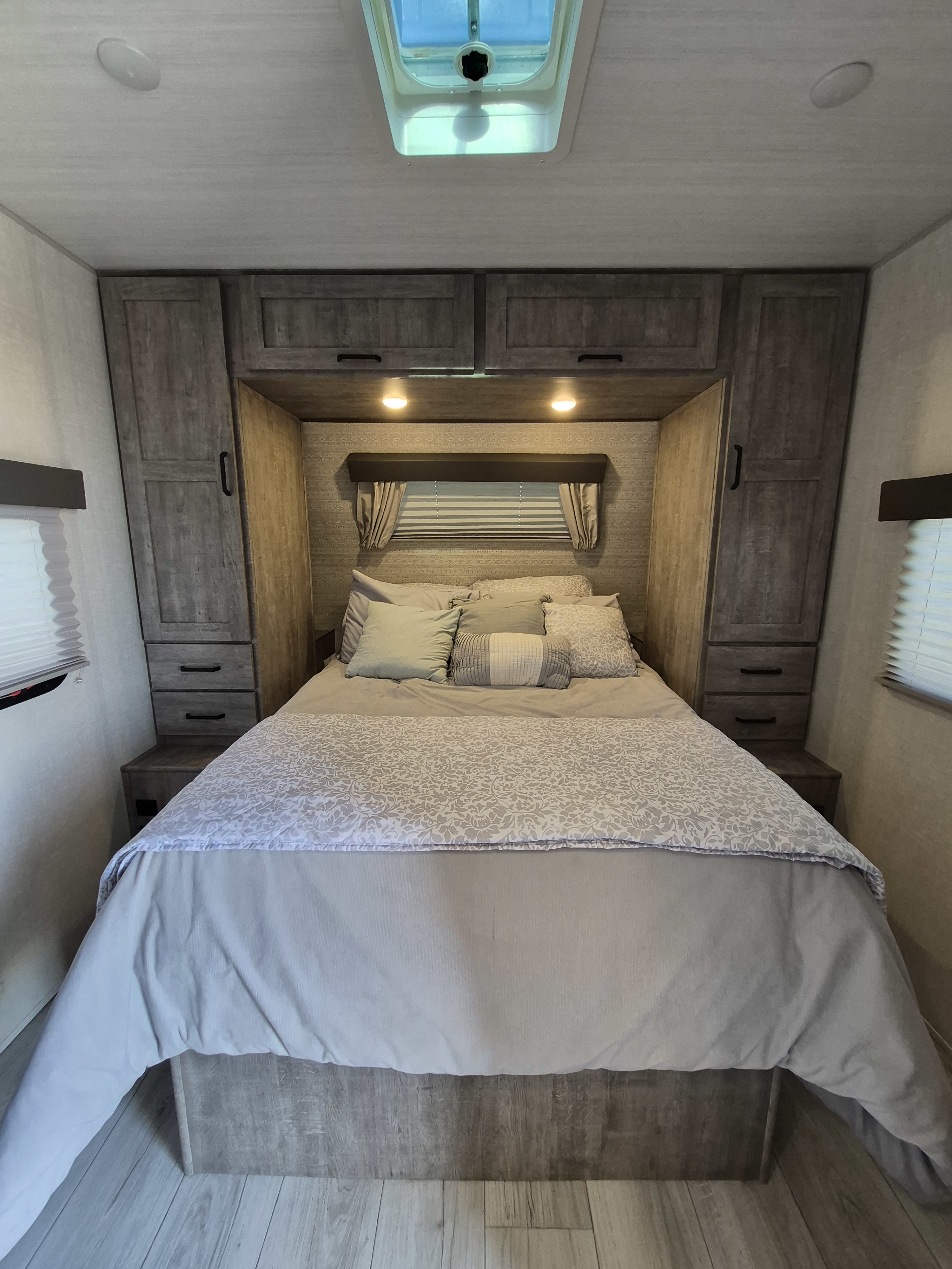 Comfortable RV rental bedroom with light bedding, built-in cabinets, and a skylight for a bright, airy feel.. Forest River Surveyor Legend 2023