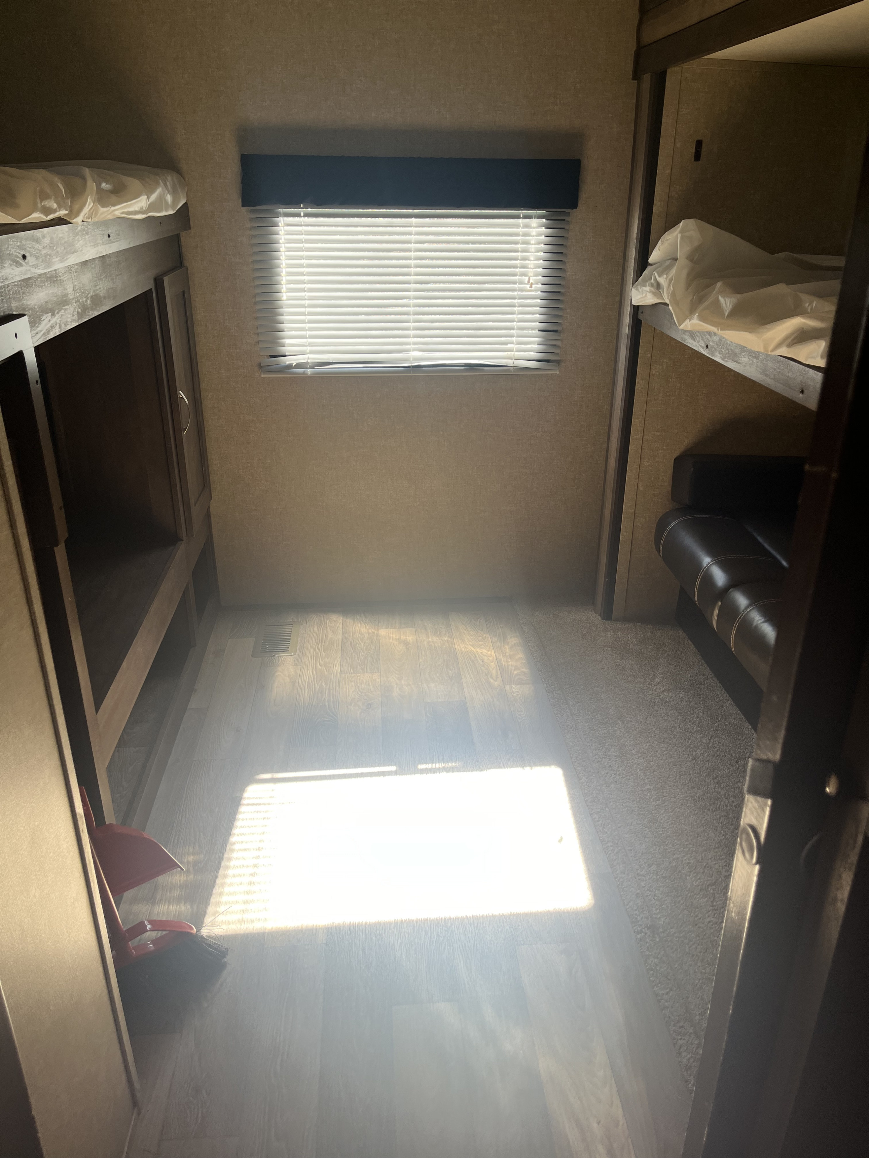 This RV rental bunkhouse features sunlit wood floors, window blinds, and cozy bunk beds with an adjacent leather seat.. Forest River Vibe Extreme Lite 2019