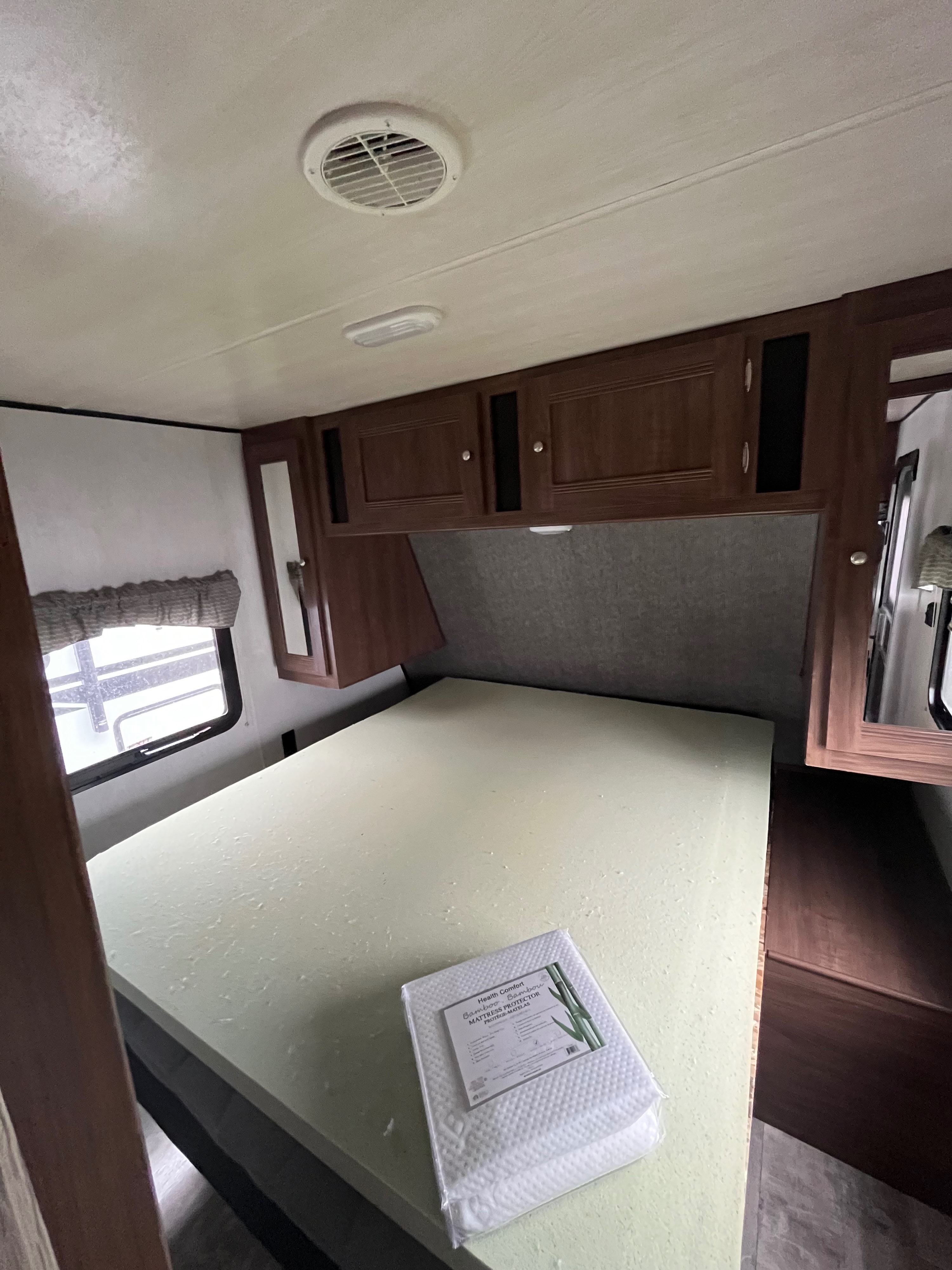 RV rental bedroom with clean foam mattress, new bamboo protector, overhead storage, and window. Ready for your adventure.. Pioneer Bunkhouse 2019