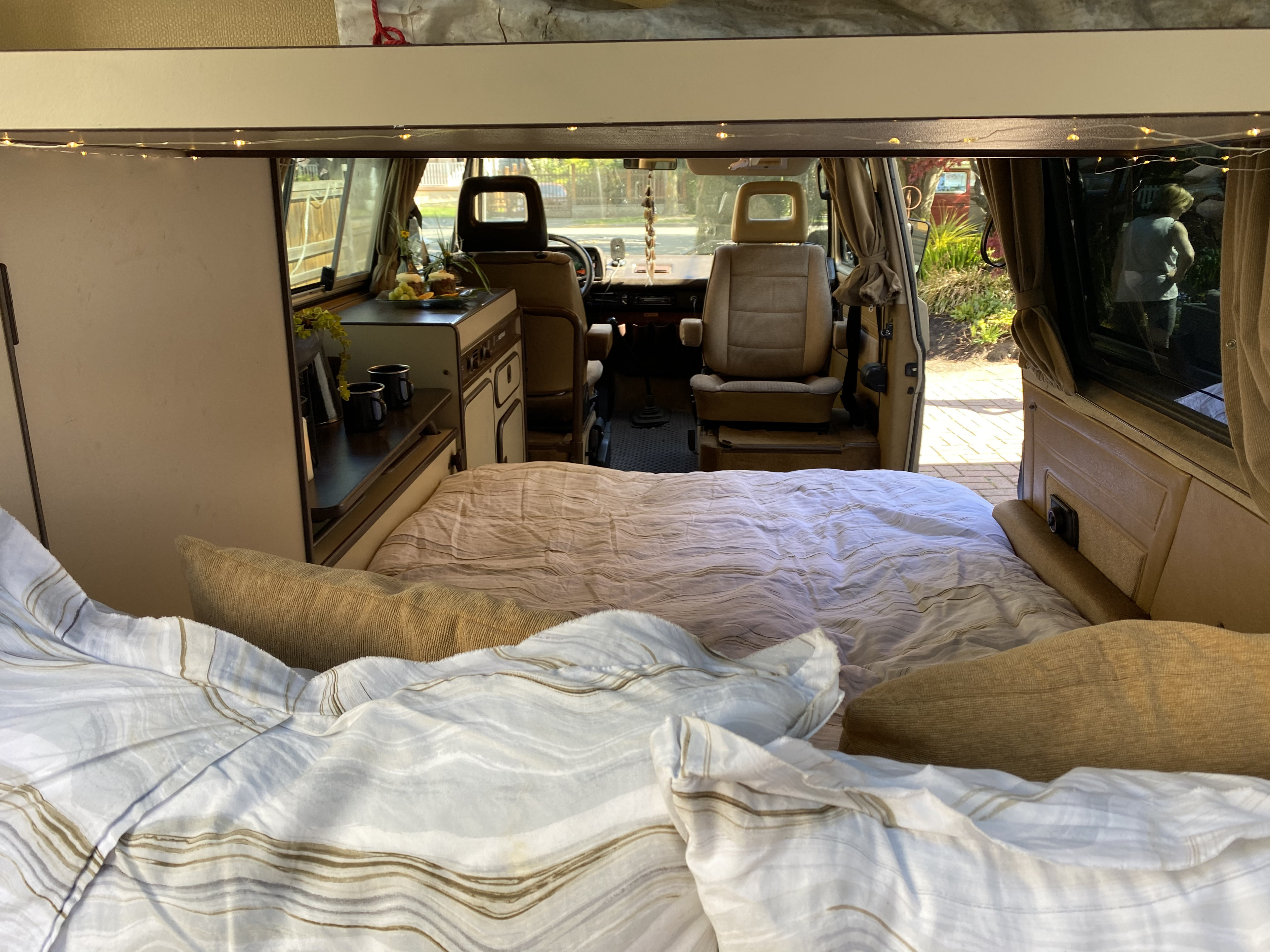 Step into this inviting RV rental: a comfy bed, compact kitchen, and driver's area visible, perfect for memorable road trips.. Volkswagen T3 Westfalia 1985