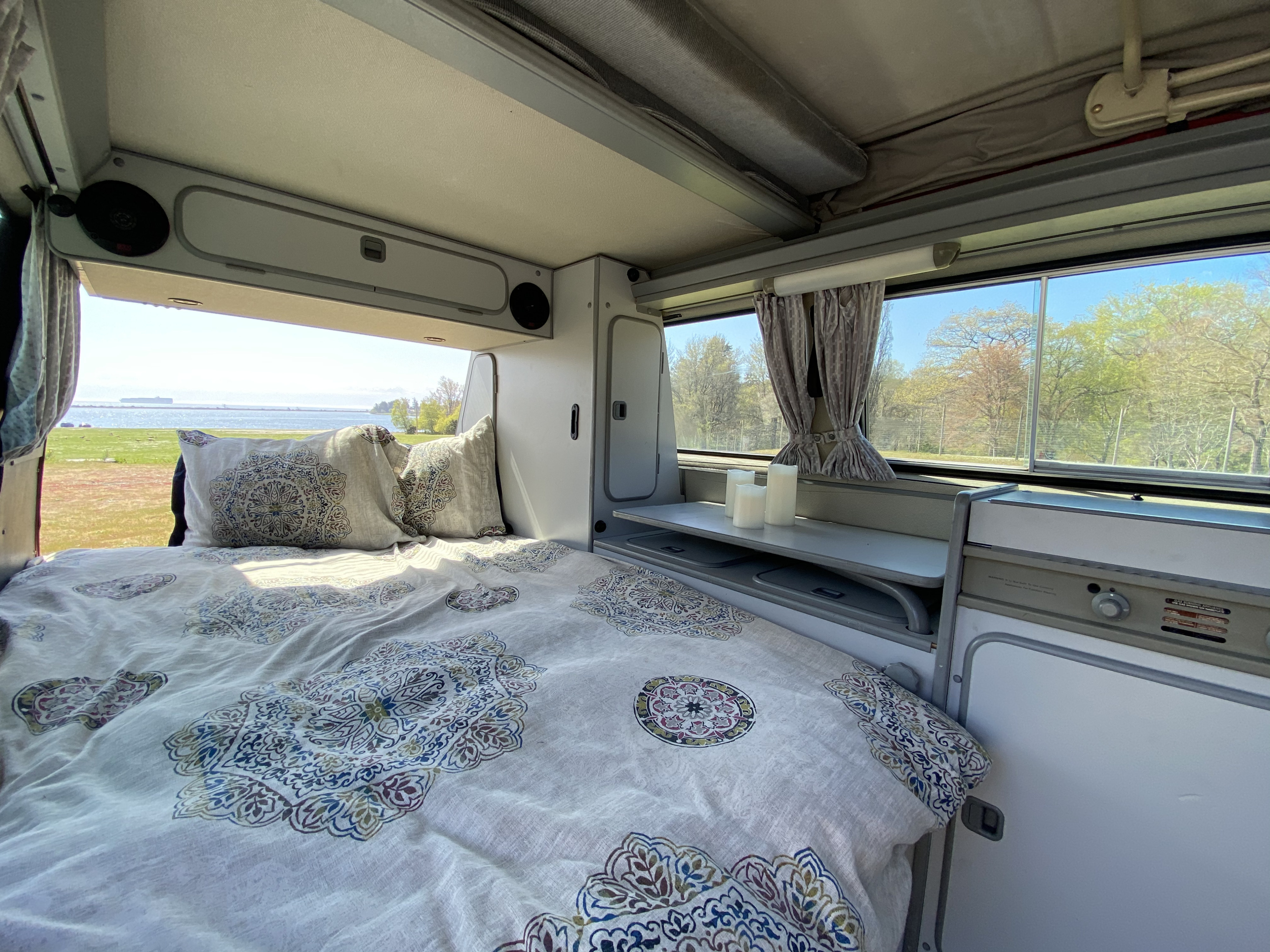 Scenic rv rental experience: a comfortable bed with mandala bedding, overlooking a beautiful ocean view & distant ship.. Volkswagen Westfalia 1986