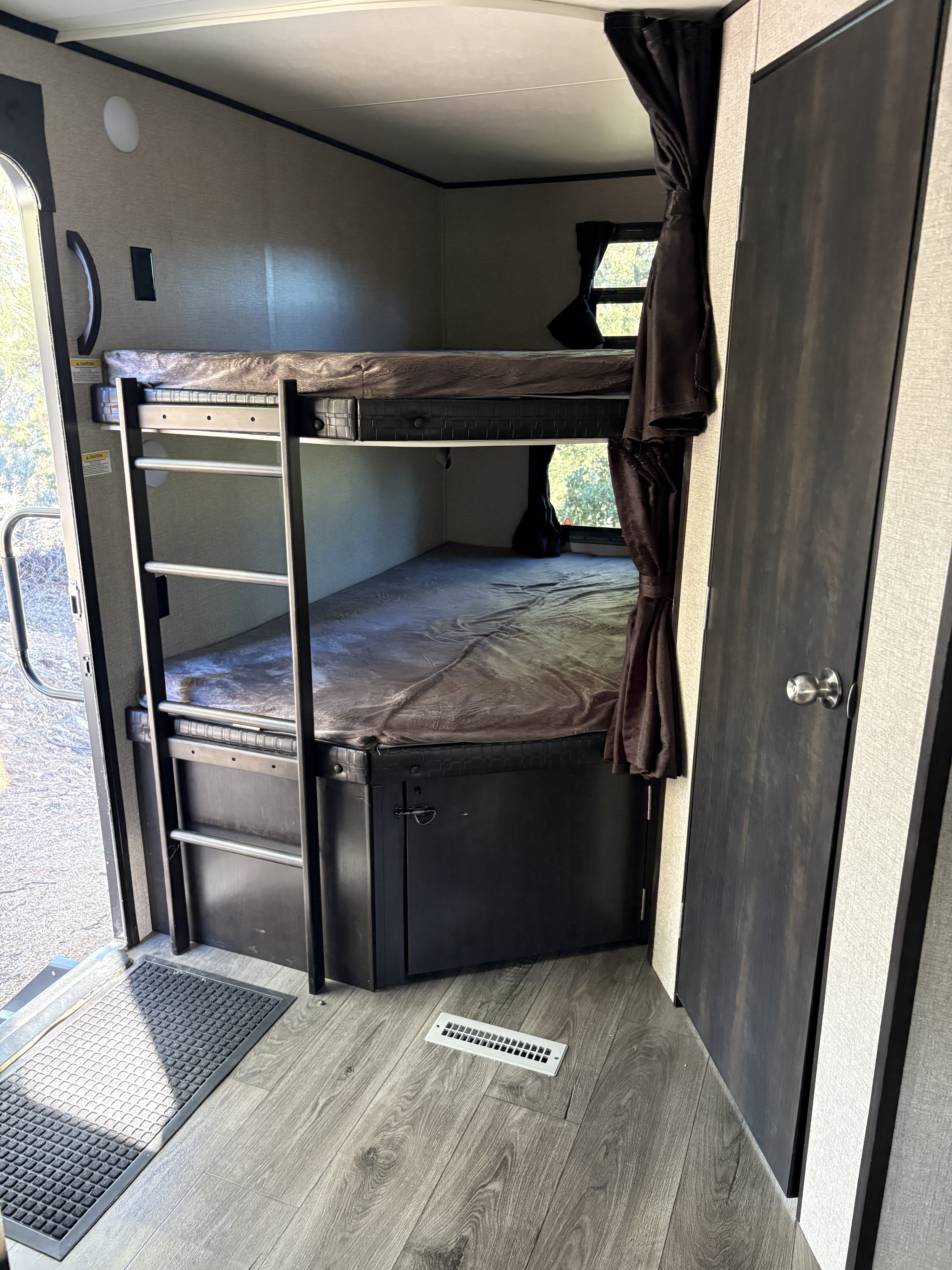 Inside this cozy RV rental, bunk beds with a ladder, storage, and a door offer practical accommodations for travelers.. Jayco Jay Flight 2021