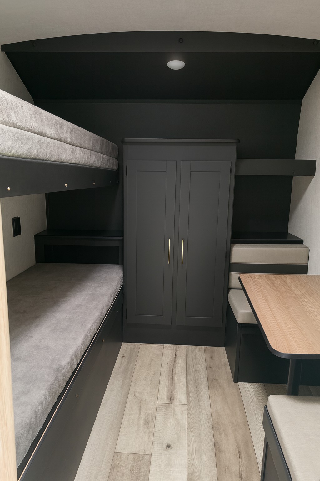 Interior of an RV rental showing stacked bunk beds, a central closet, and a dinette with bench seating and light wood floor.. Keystone RV Springdale 2024