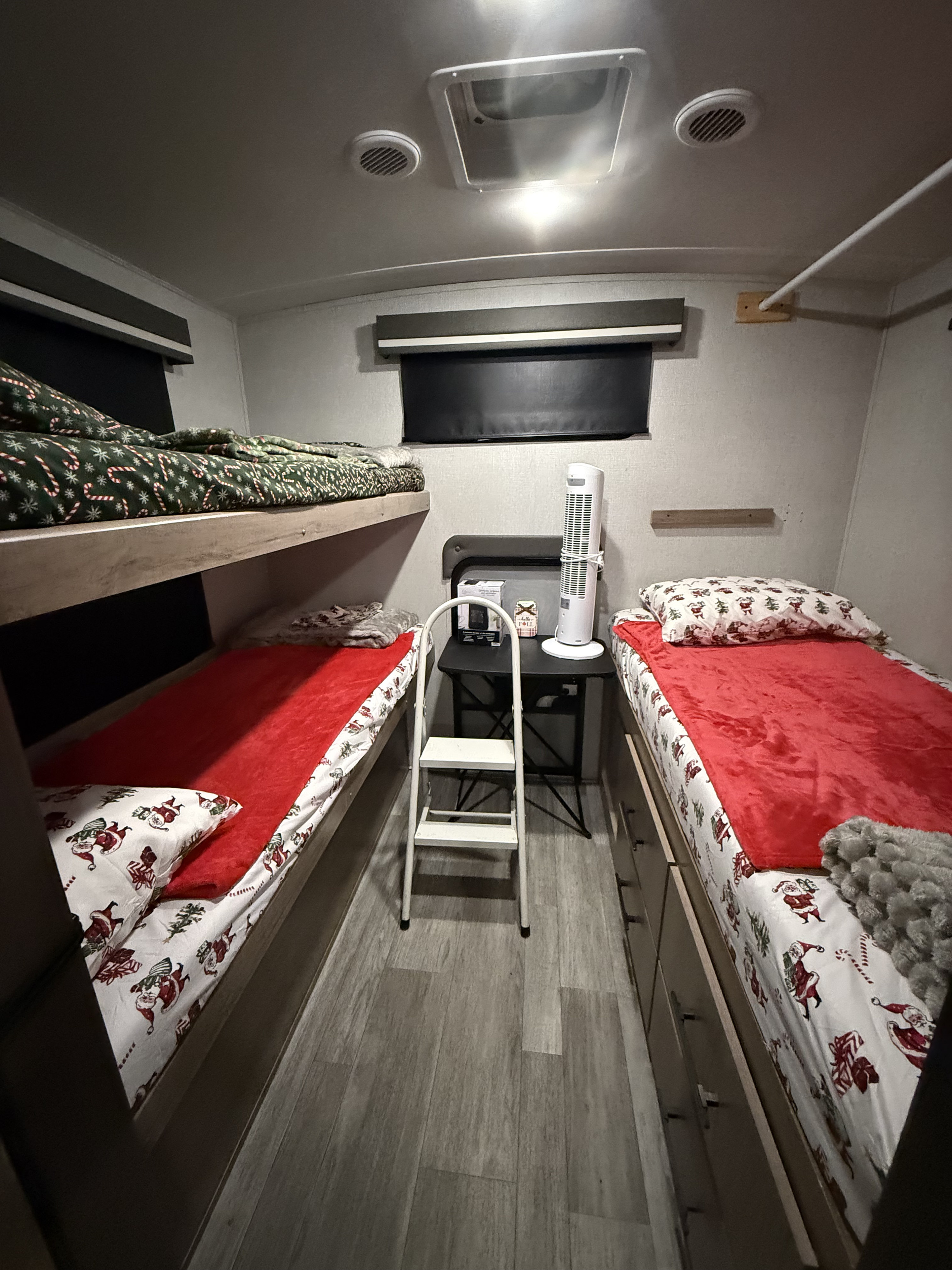 Cozy RV rental sleeping area featuring bunk beds with festive holiday sheets, a fan, and a step stool.. Grand Design Imagine 2023