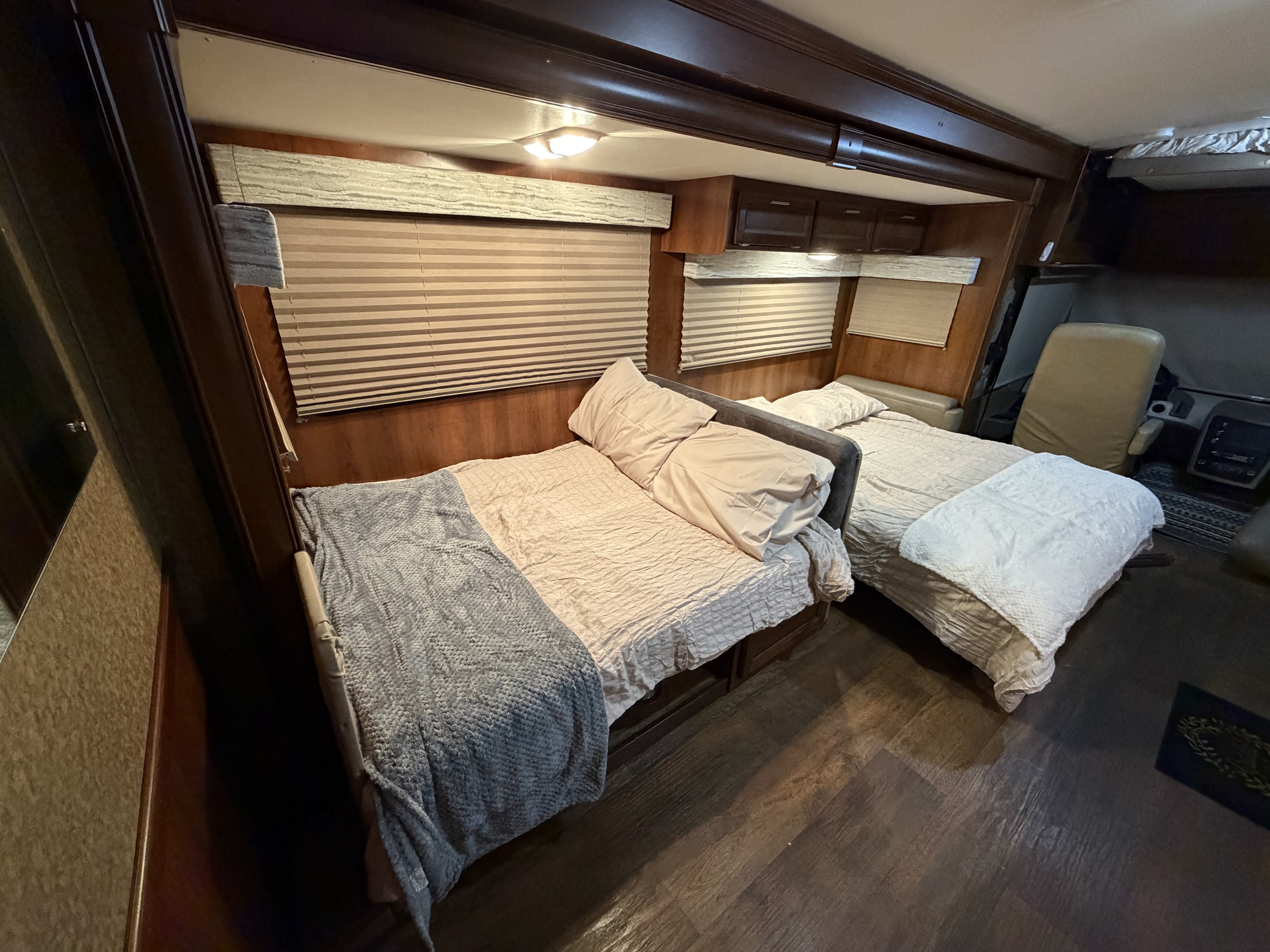 Cozy rv rental sleeping area featuring two beds with light bedding, window blinds, and rich wood interior finishes.. FR3 FR3 Motorhome 2015
