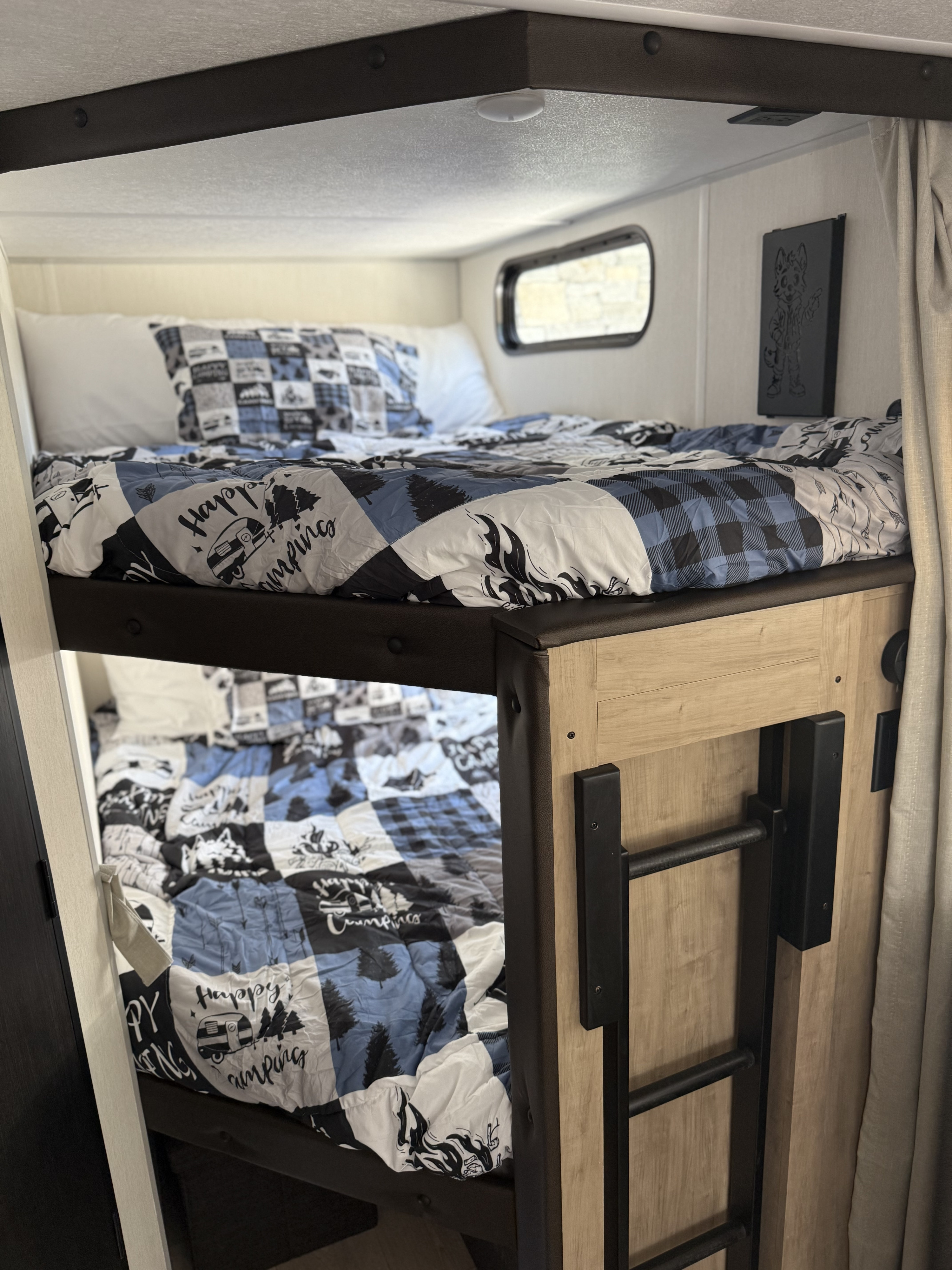 Comfortable bunk beds with camping-themed bedding in this RV rental, featuring a ladder and window for a great family camping experience.. Forest River Cherokee Grey Wolf 2026