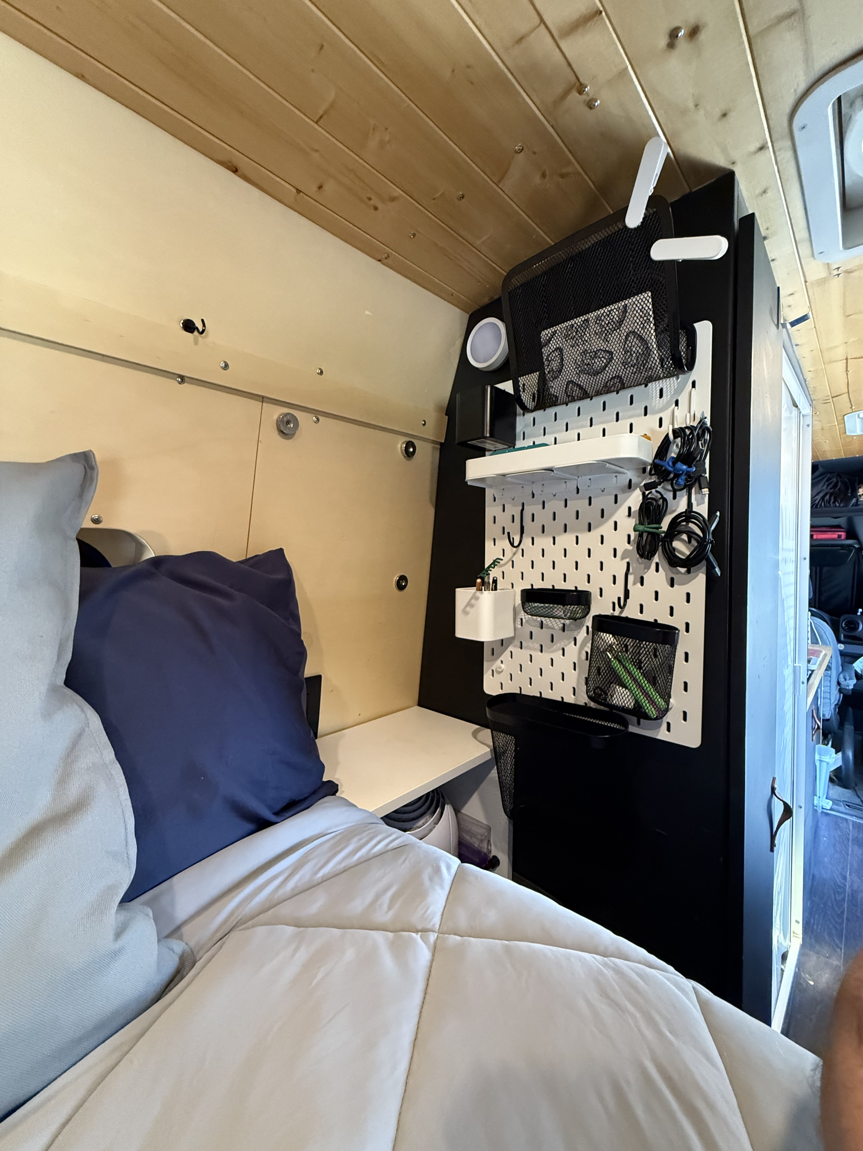 Cozy rv rental interior featuring a bed, an integrated nightstand, and a pegboard organization system for efficient storage.. Mercedes-Benz Sprinter 2019