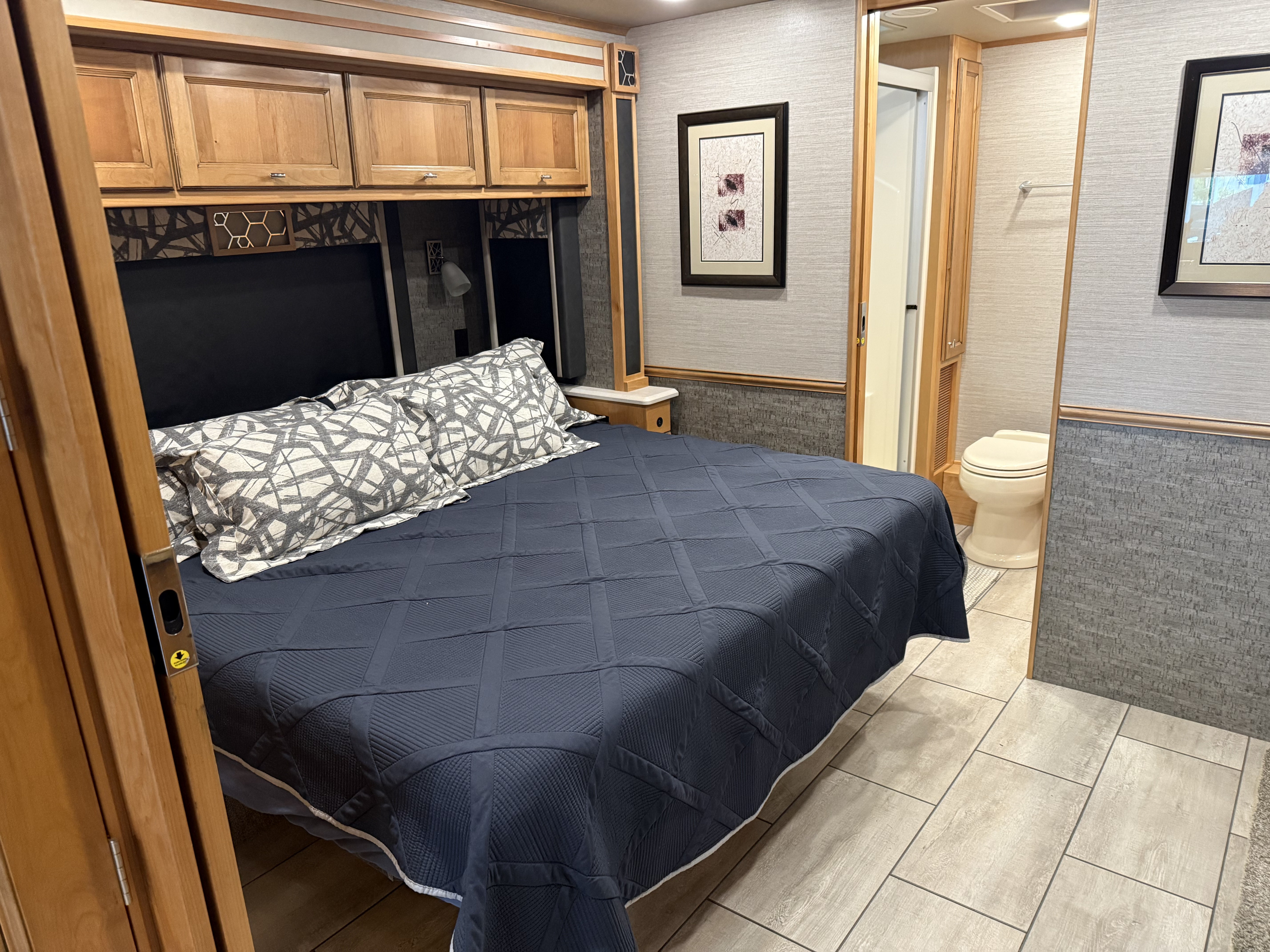 Spacious RV rental bedroom with bed, overhead storage, and adjacent bathroom.. Allegro Allegro Open Road 2020