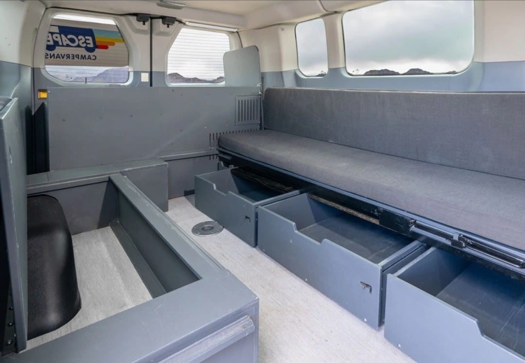 RV rental campervan interior: gray modular seating, pull-out storage, and bed setup ready for adventure.. Ford Transit 2017