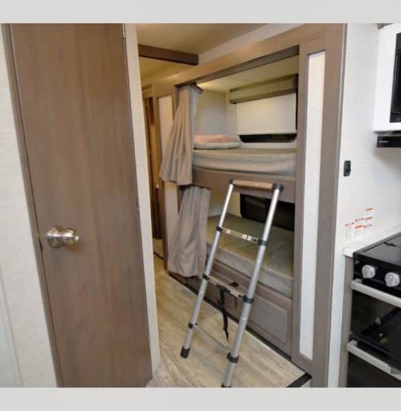 This RV rental interior features bunk beds, a ladder, and privacy curtains, offering comfortable sleeping arrangements for guests.. Thor Motor Coach Chateau 2024